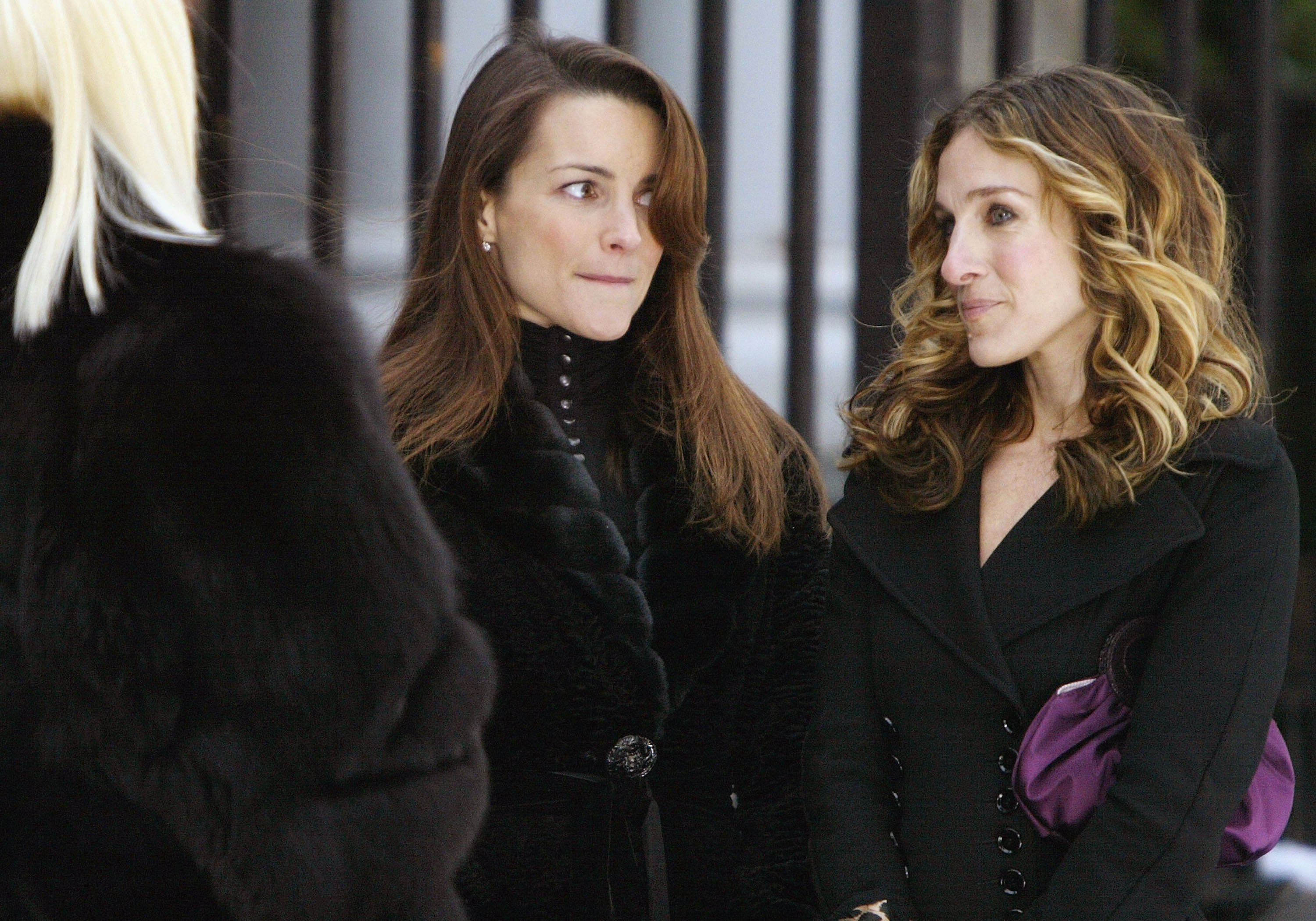 Kristin Davis and Sarah Jessica Parker wearing black coats while filming “Sex And The City” in New York.