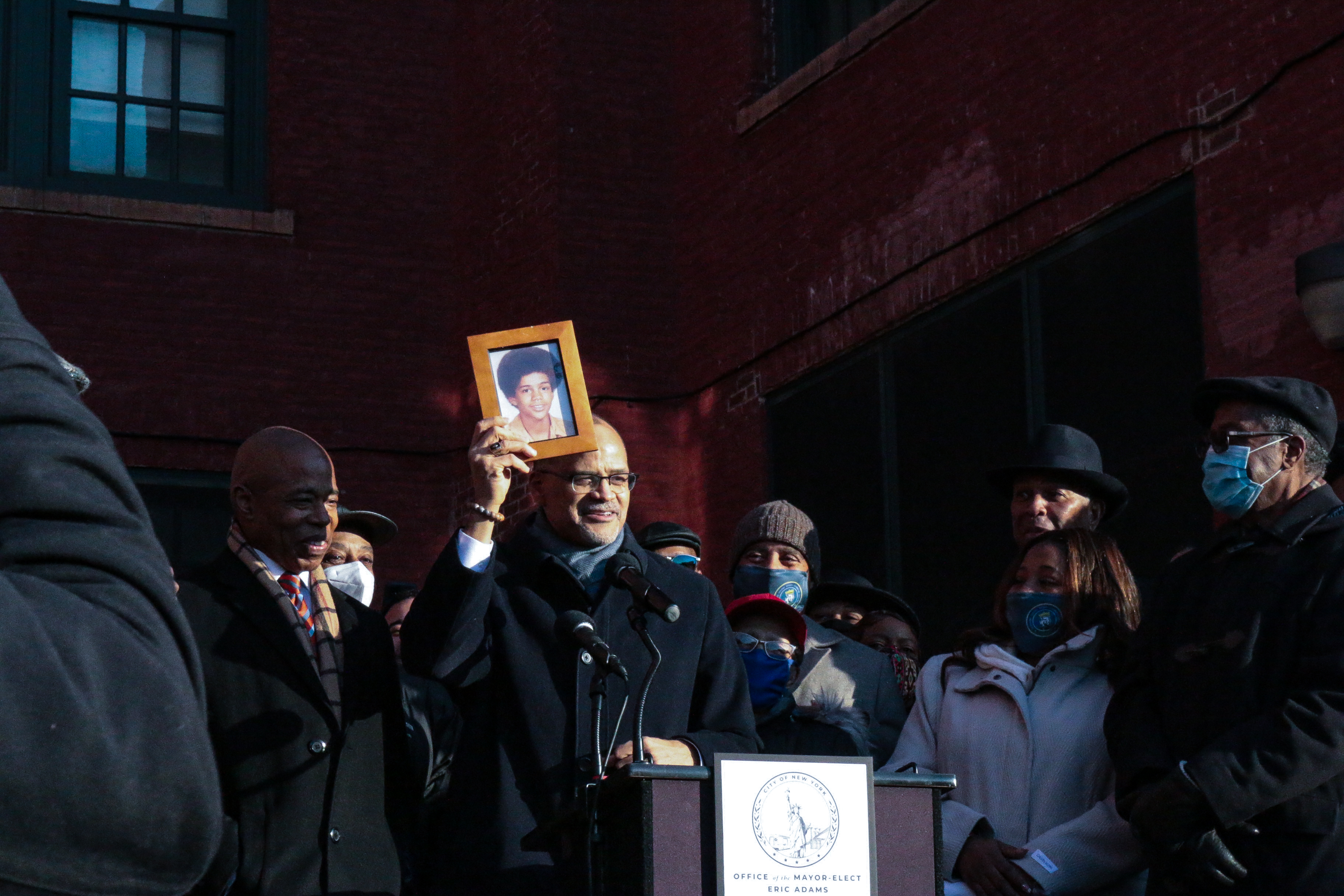 A man at a lectern holds up a framed photo.