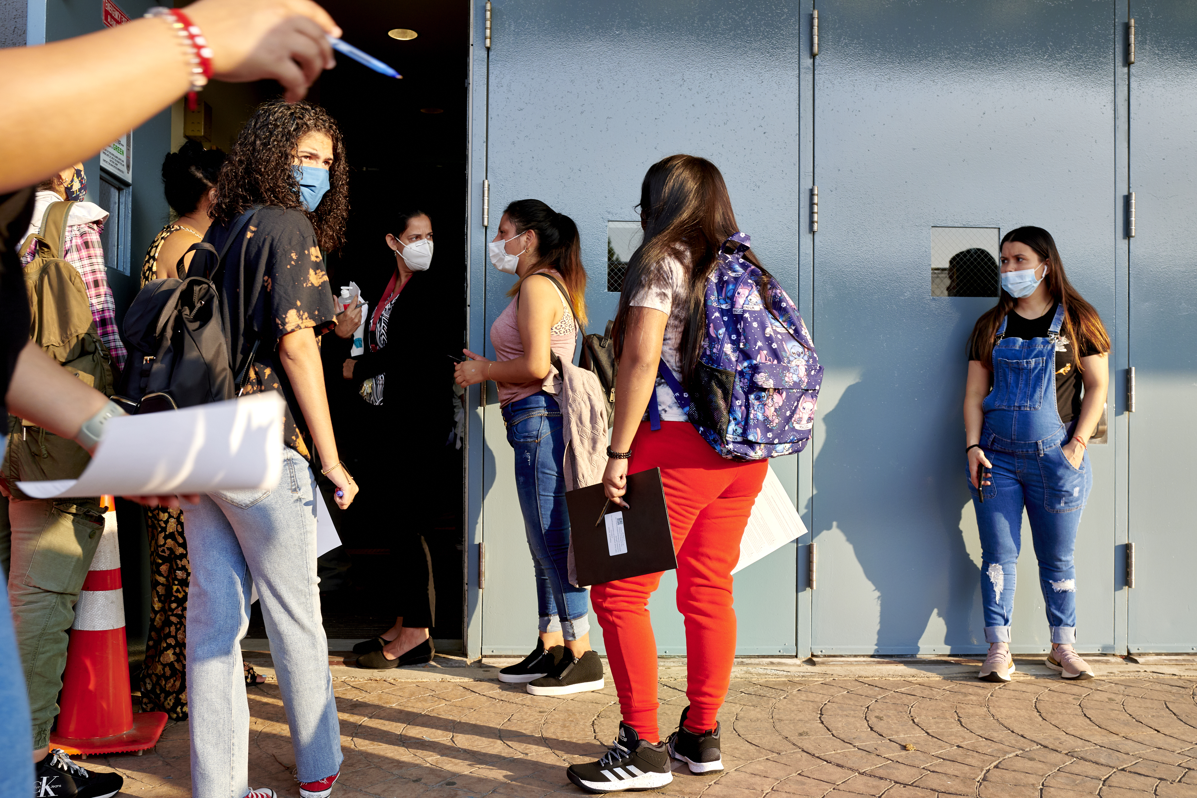 Students wait to enter the blue doors of their high school as faculty direct them on the first day of classes.