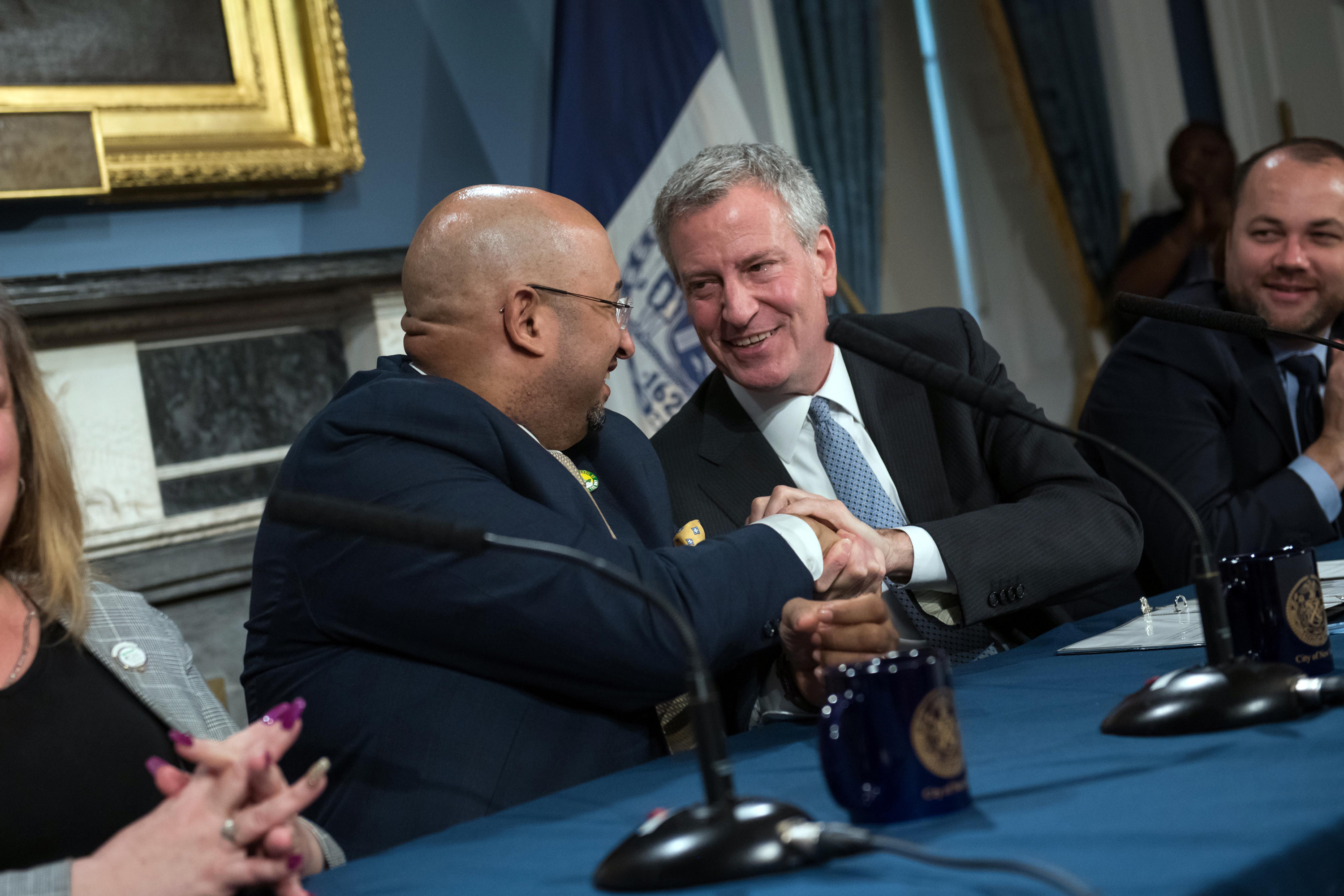 Mayor Bill de Blasio shakes hands with District Council 37 Executive Director Henry Garrido after announcing a contract agreement in 2019.