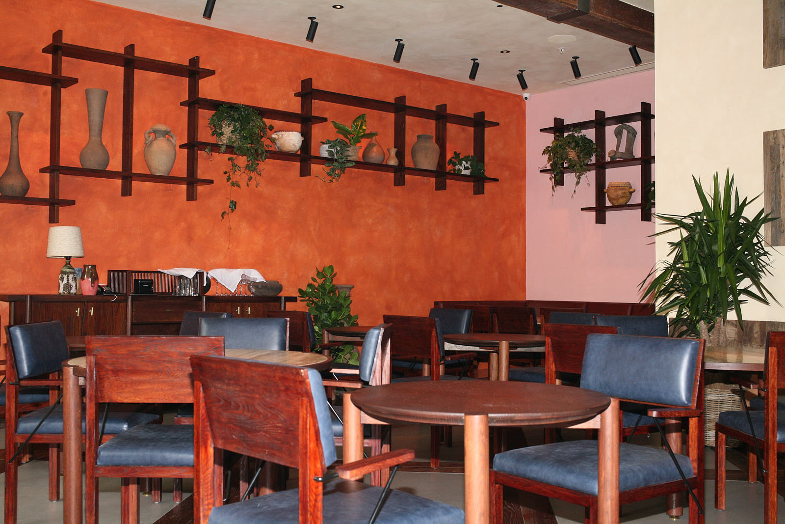 Inside Kol, with an earthy toned dining room design complete with Mexican ceramics on wooden shelves on the walls