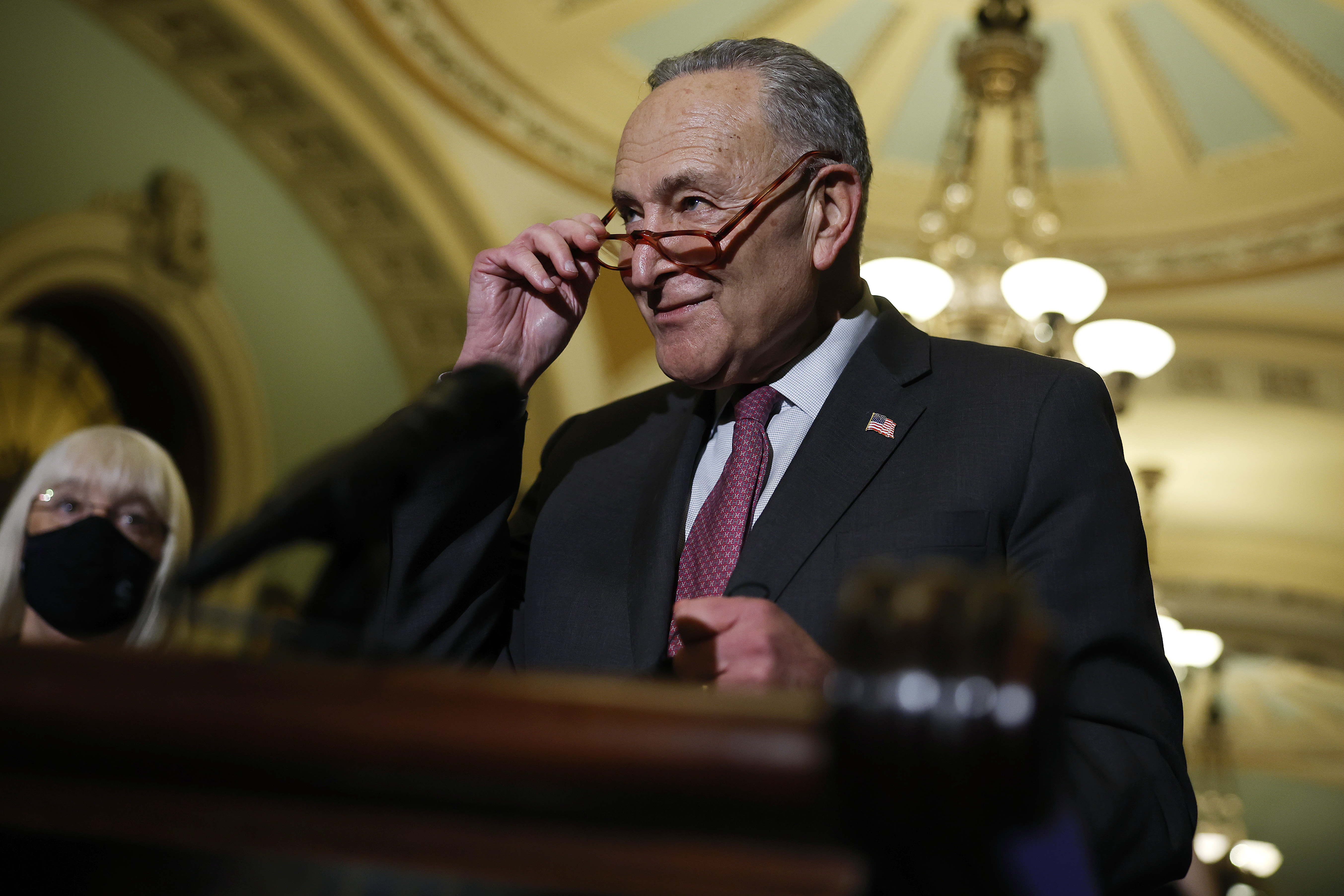 Senate Majority Leader Chuck Schumer adjusts his glasses as he speaks to reporters on Capitol Hill.