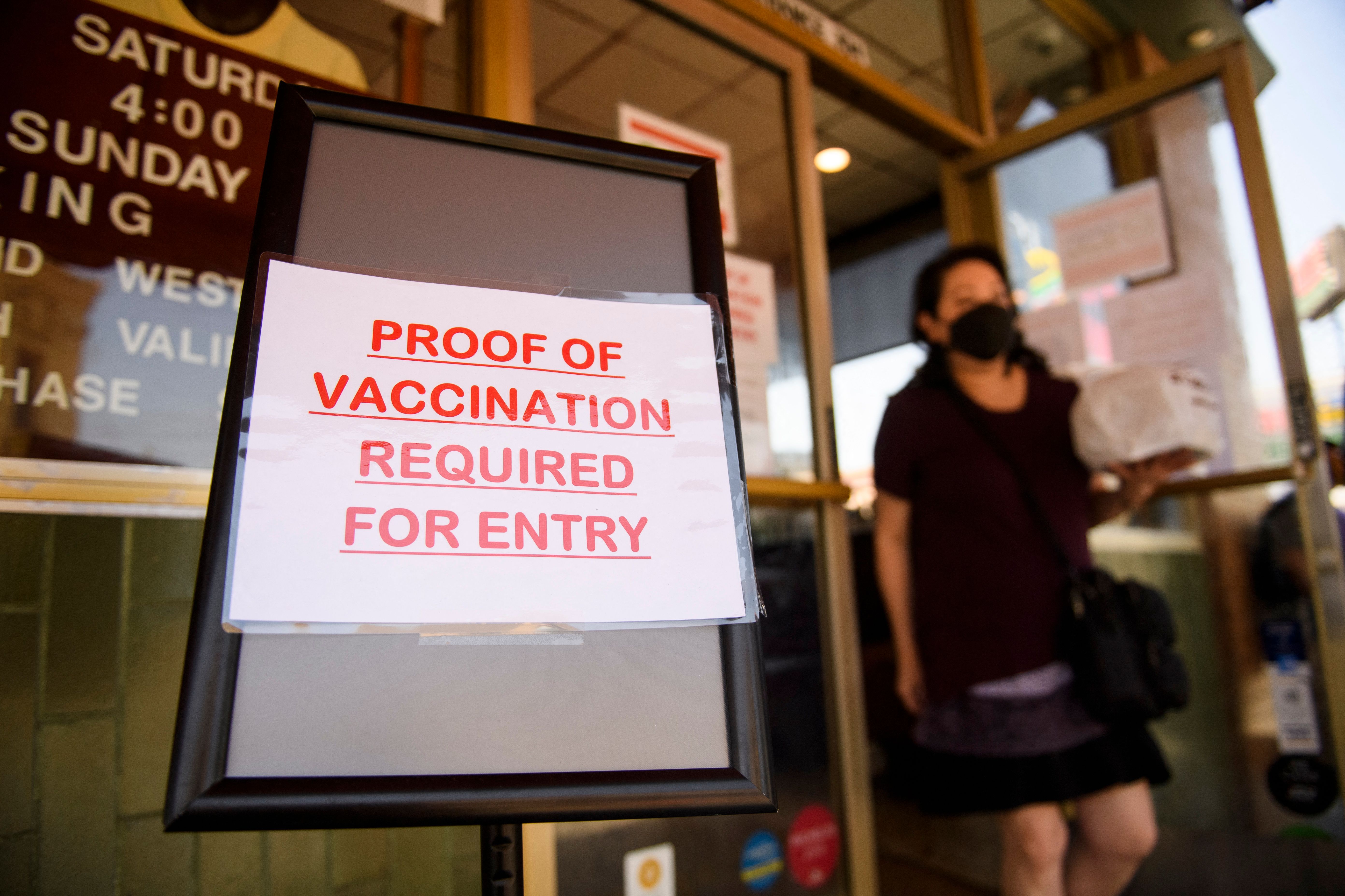 A sign stating proof of a Covid-19 vaccination is required is displayed outside of Langer’s Deli in Los Angeles.