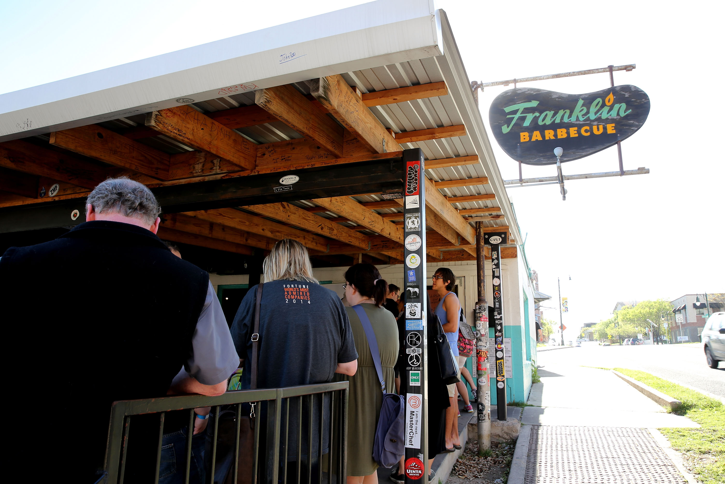 People waiting on a patio line for Franklin Barbecue.