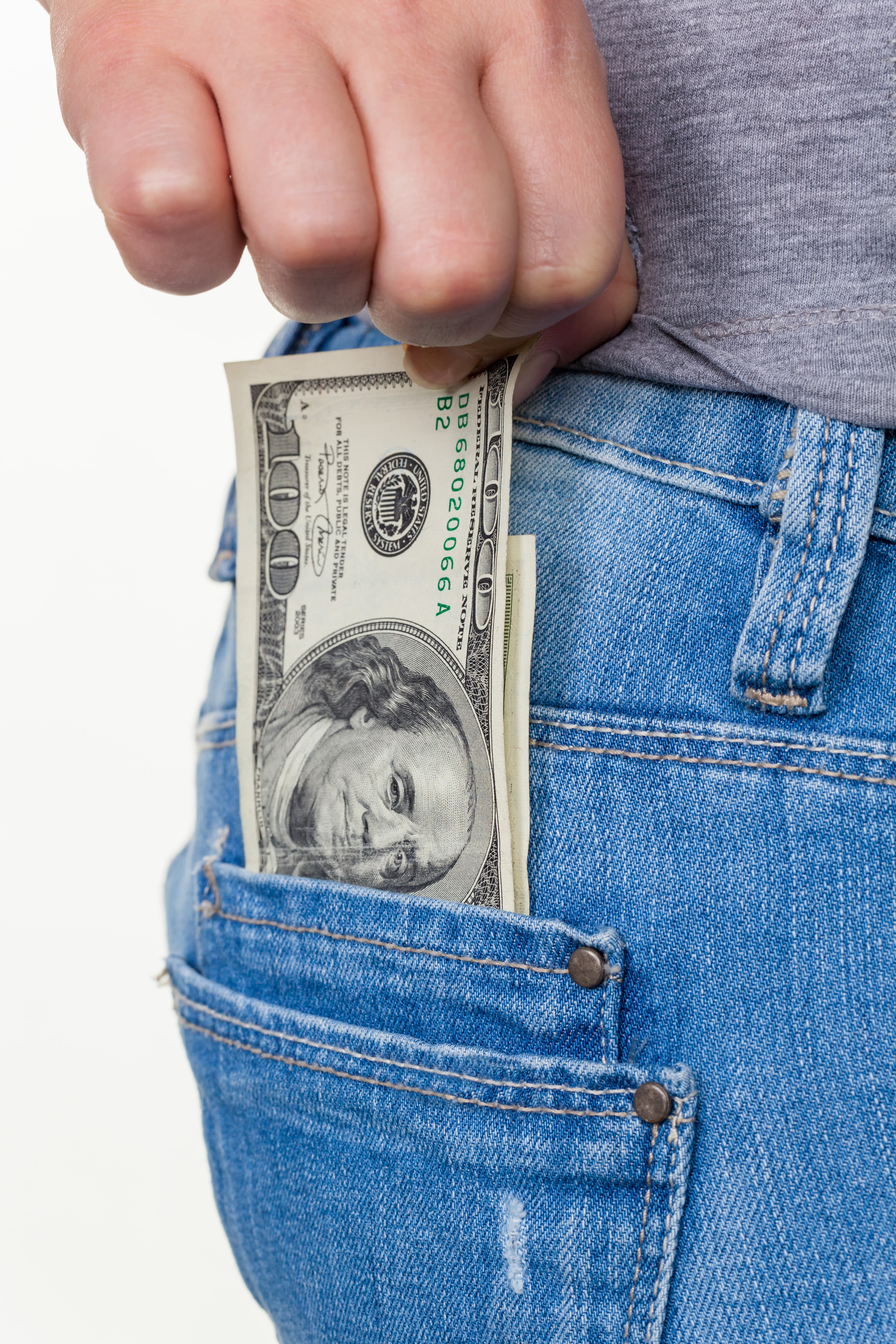 Die Hand einer jungen Frau zieht einen Dollar Geldschein aus der Tasche ihrer Jeans