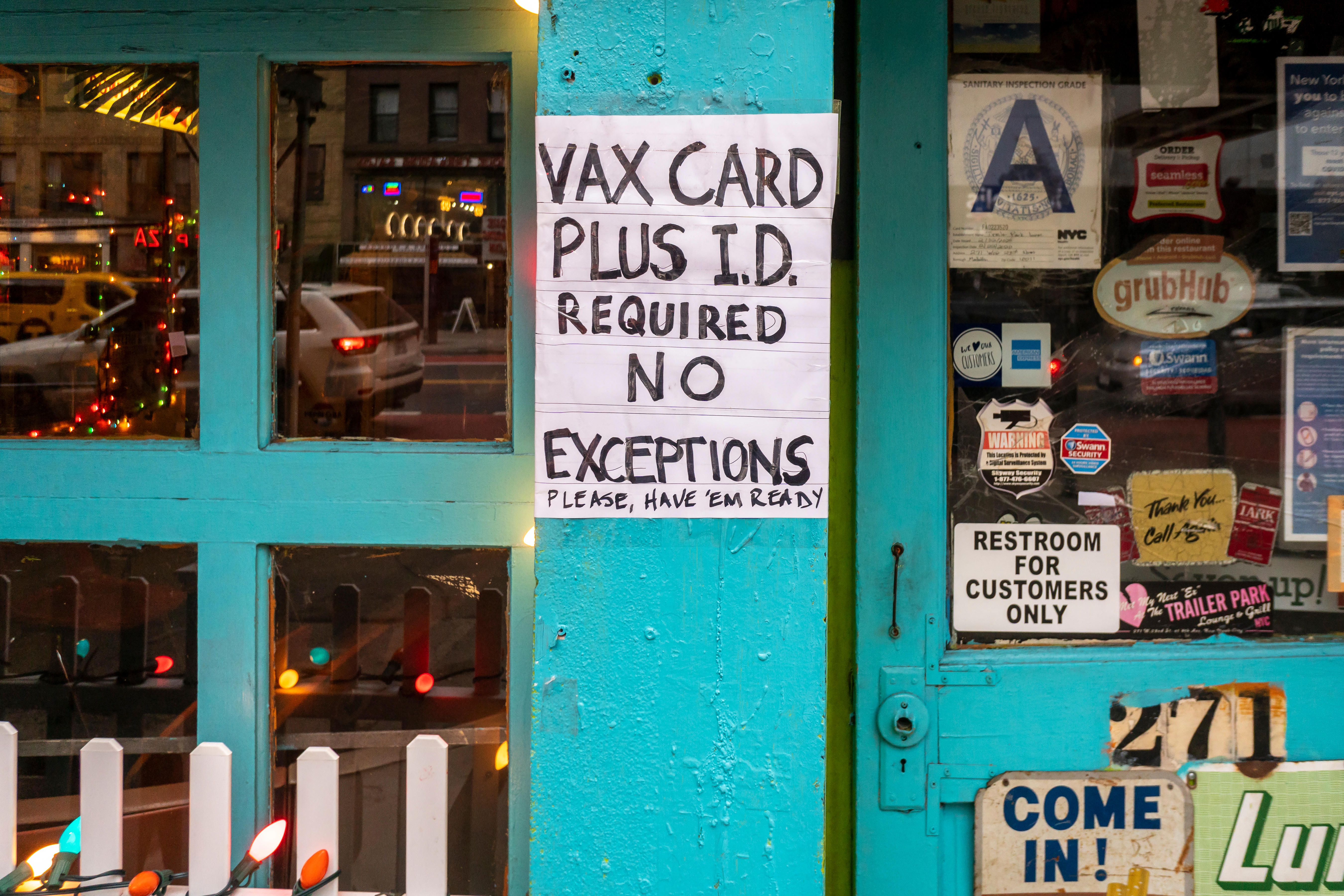 A hand-written sign outside a restaurant says “Vax card plus i.d. required. No exceptions, please have ‘em ready.”