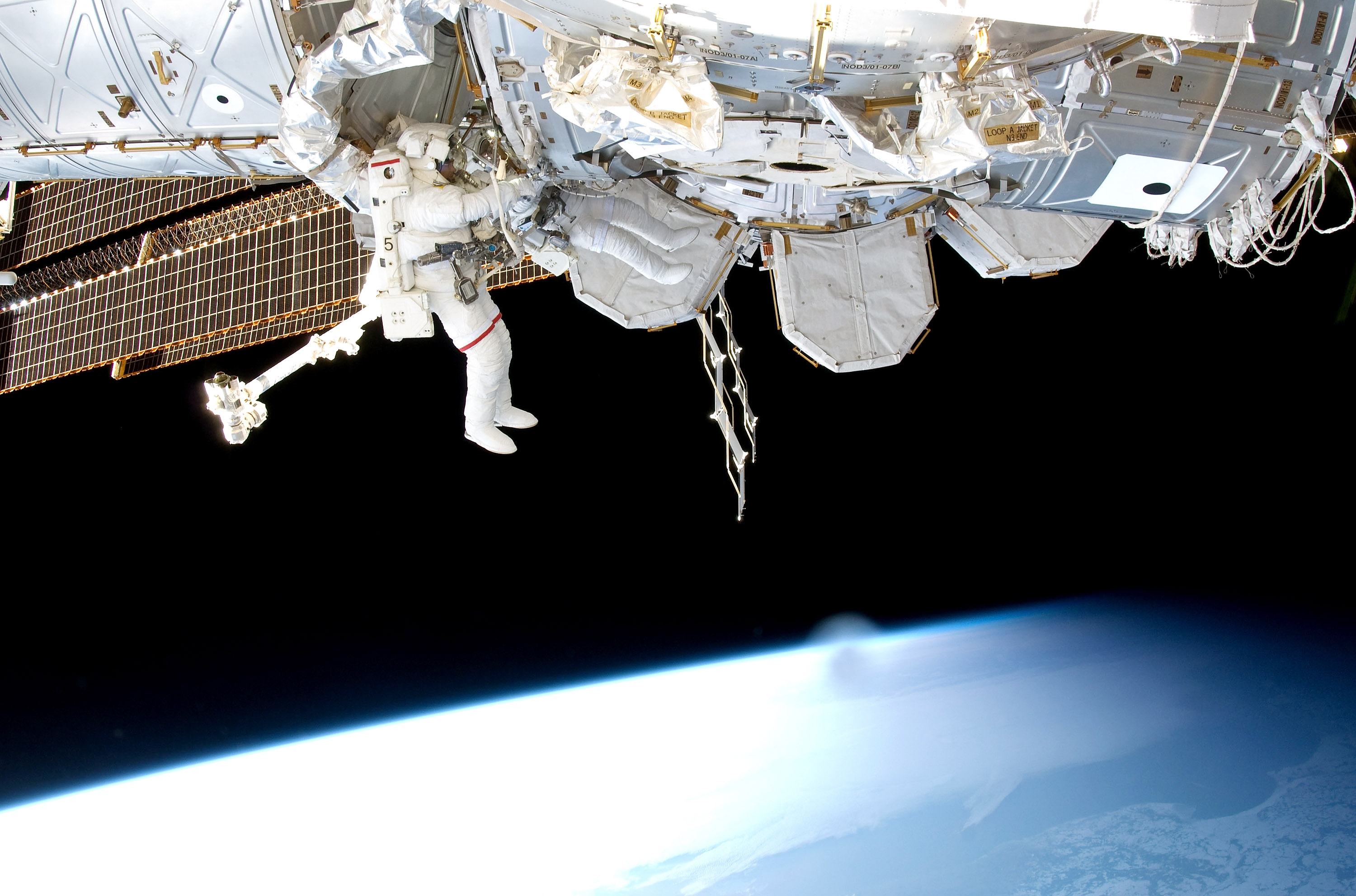 An astronaut doing construction outside the International Space Station while it orbits the Earth.