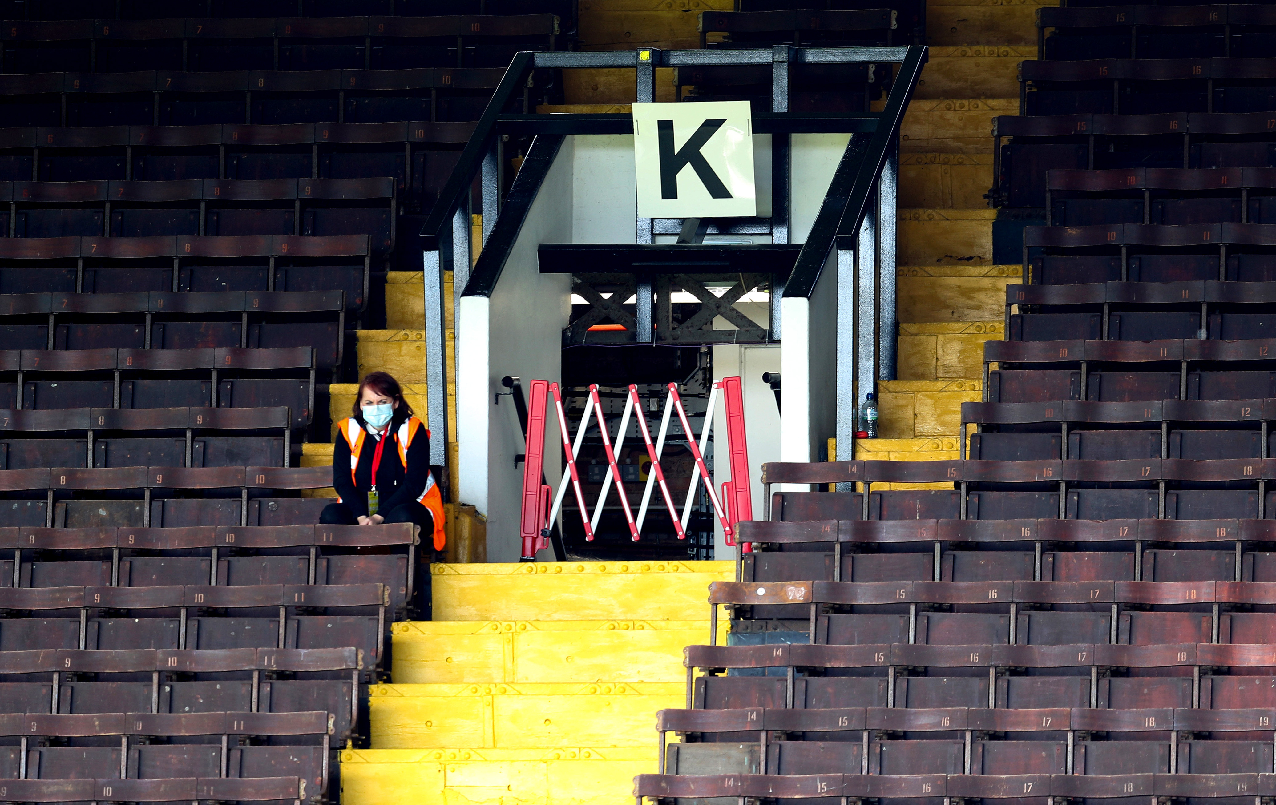 A steward wearing a protective face mask sits in the empty stand - Sky Bet Championship