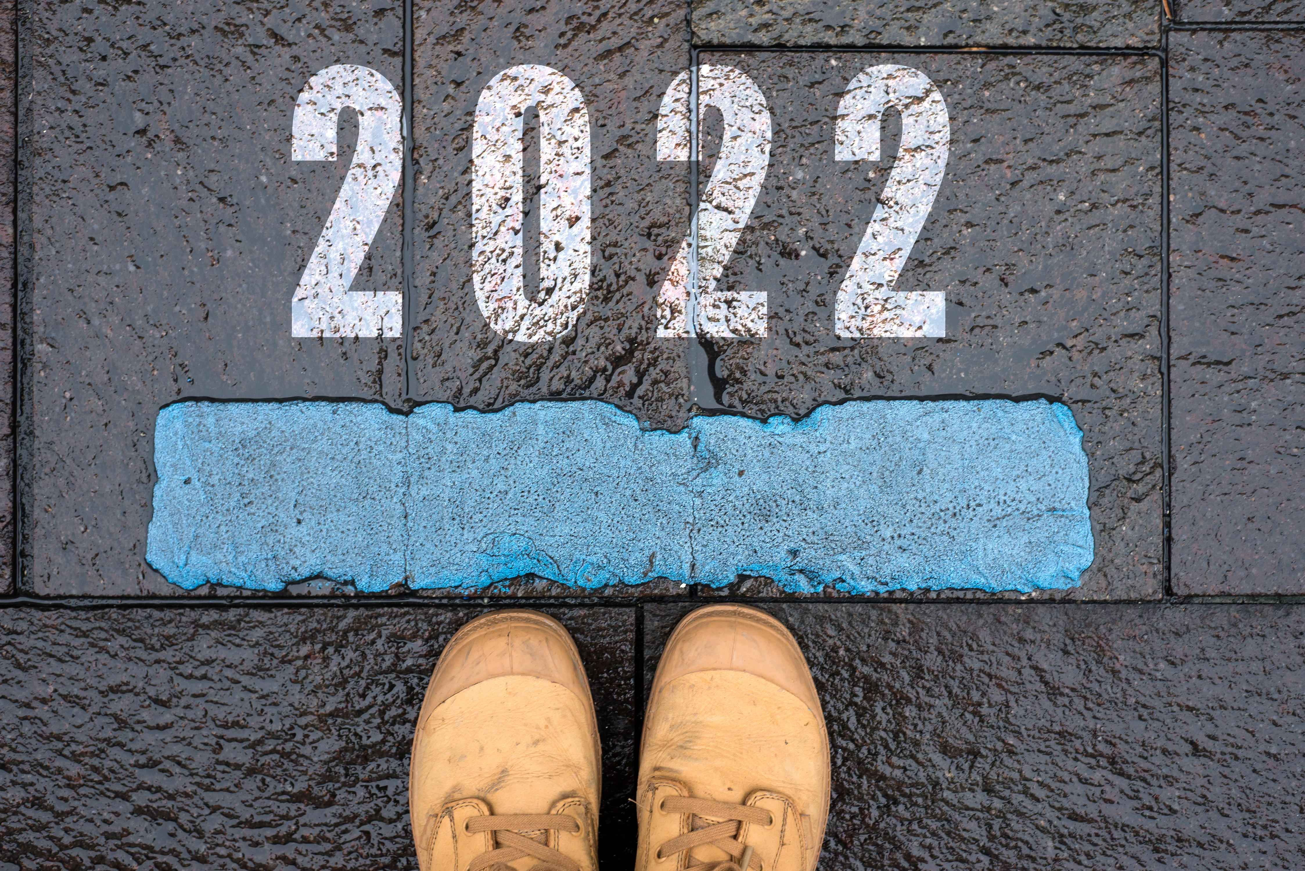 “2022” painted on the ground in front of a starting line with a pair of shoes behind the line.