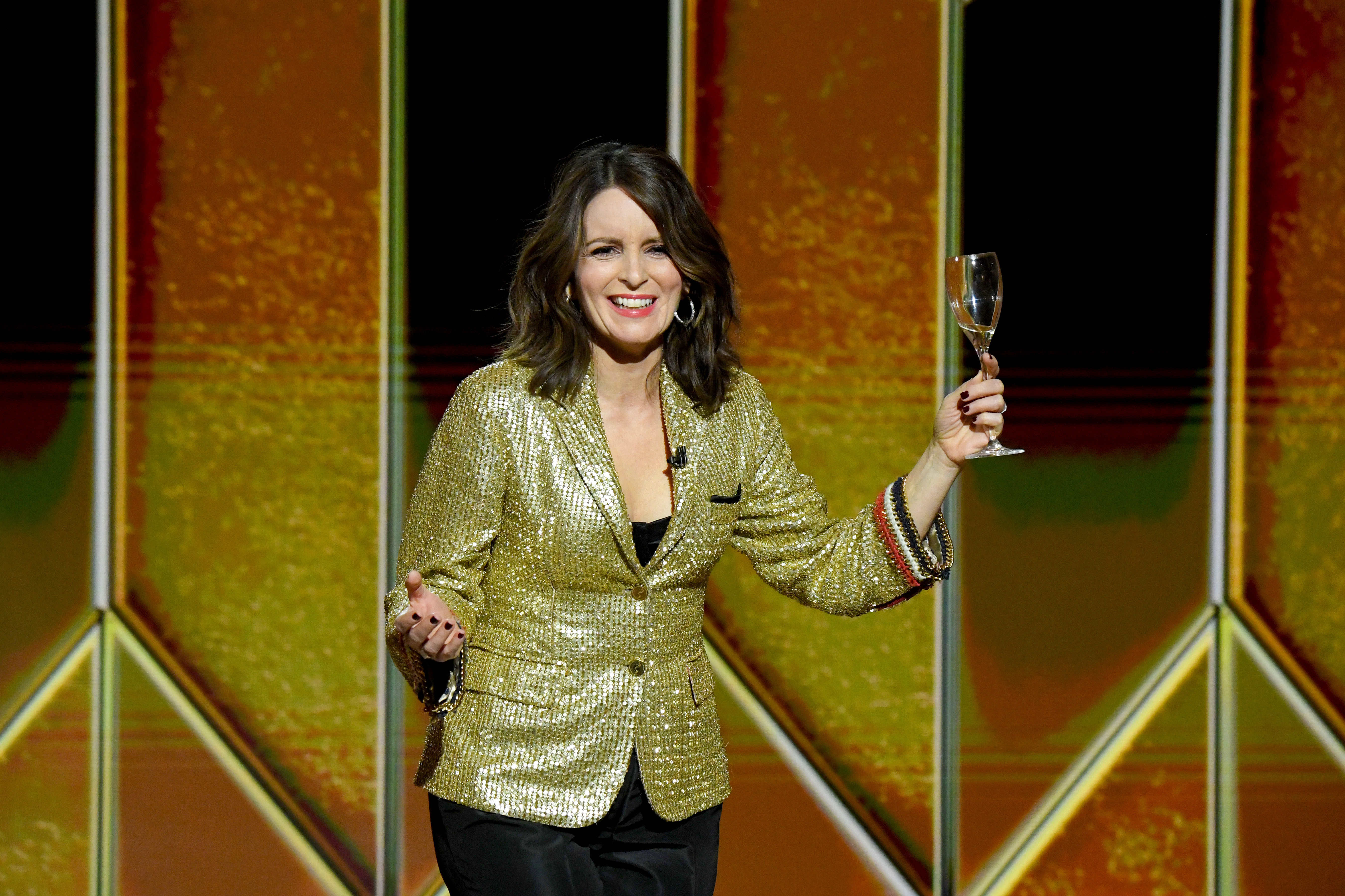 Tina Fey holds up a wineglass onstage at the Golden Globes in 2021.