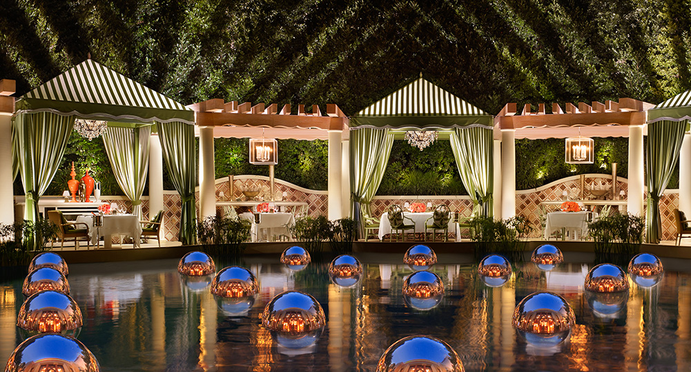 A patio with cabanas overlooking a lagoon with private cabanas in the background.