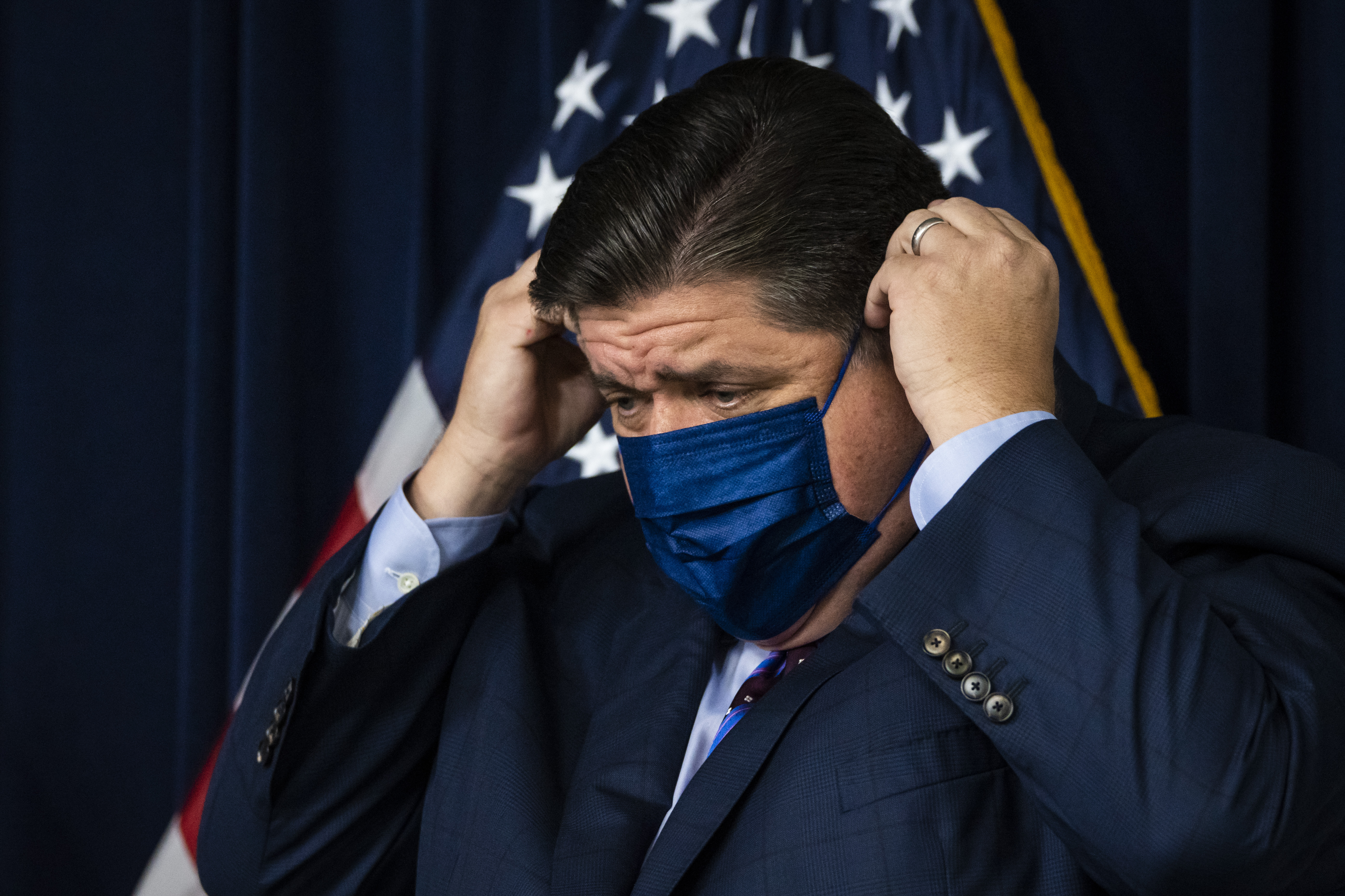Gov. J.B. Pritzker adjusts his mask at an August 2021 news conference. The governor had close contact with a state worker who tested positive for COVID-19 Tuedsay.
