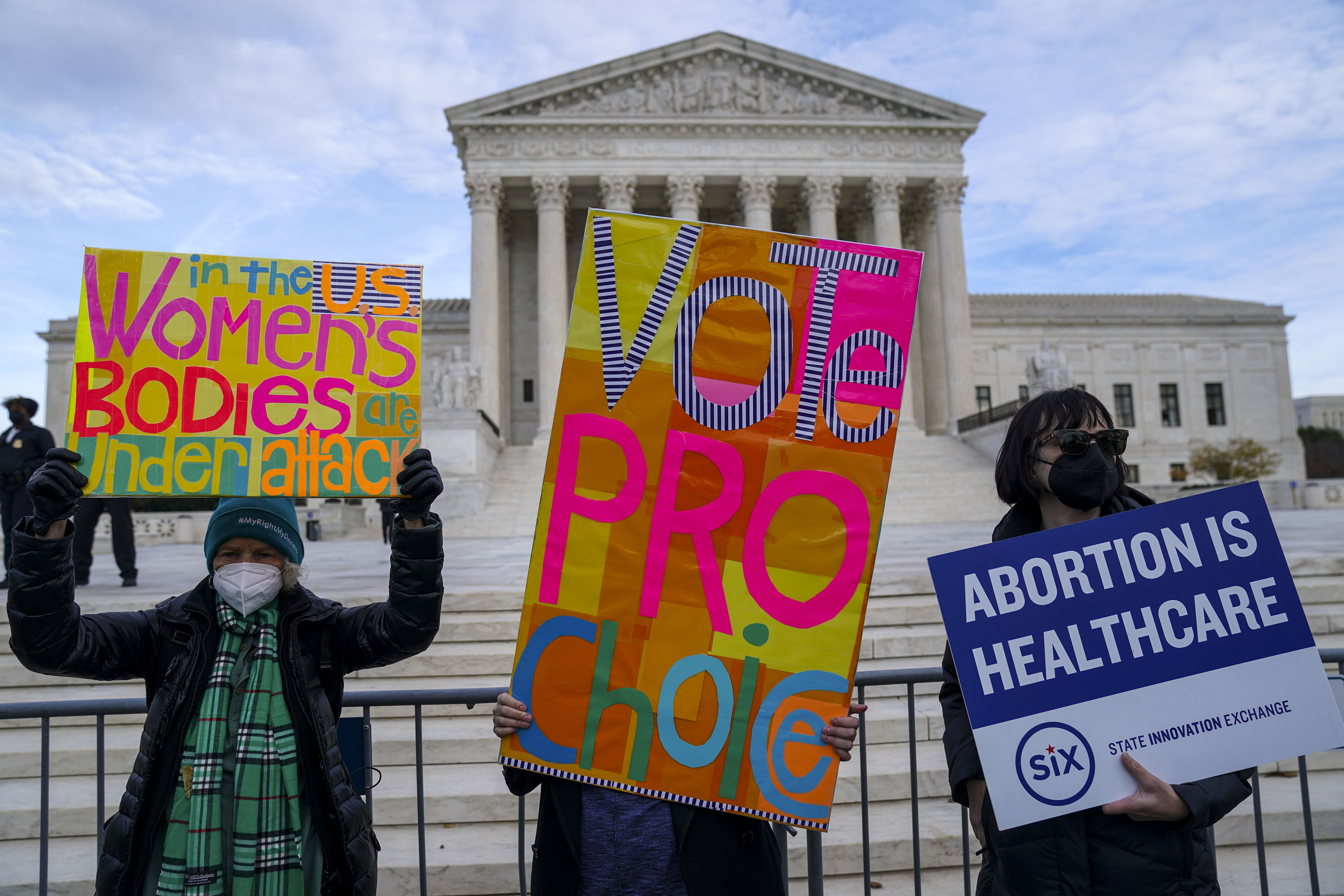 Protesters hold signs that read “Vote pro-choice,” “Abortion is healthcare,” and “In the U.S., women’s bodies are under attack.”