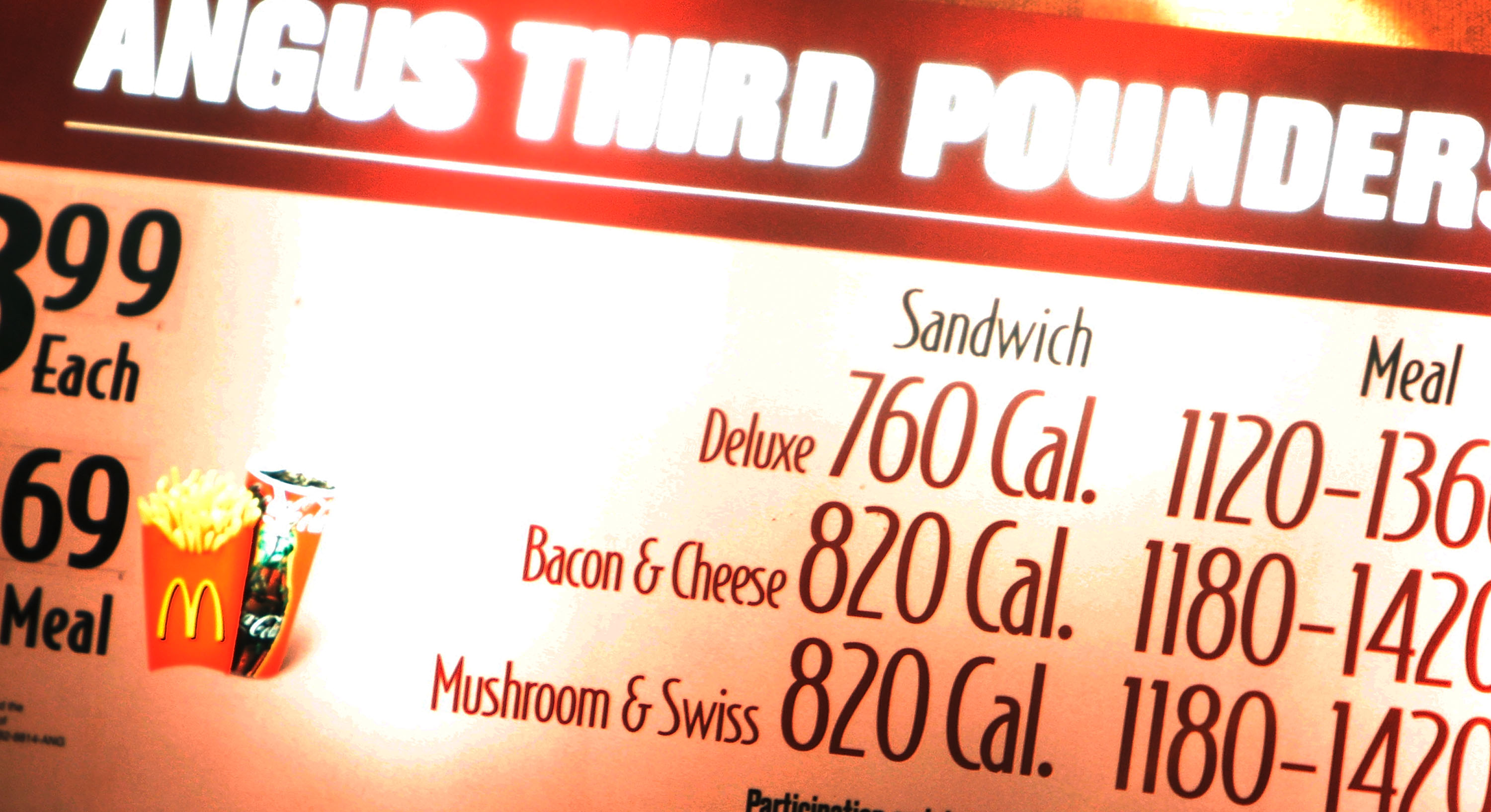 A close-up on the calorie counts listed for angus third pounders on a lit-up McDonald’s menu board.