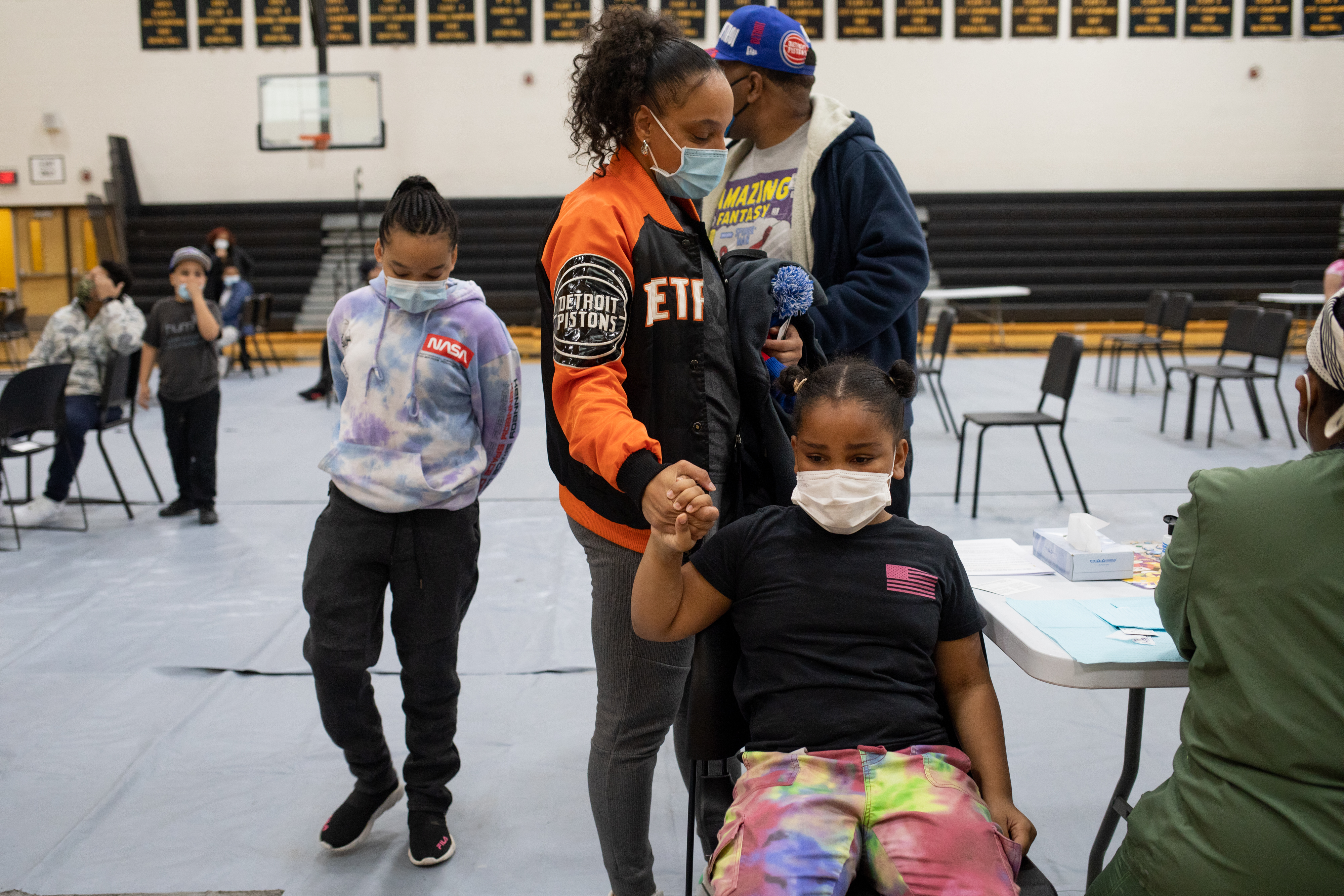 A girl holds her mom’s hand as she gets ready to receive her first dose of the Pfizer-BioNTech coronavirus disease (COVID-19) vaccine during a pediatric vaccine clinic at Martin Luther King, Jr. Senior High School in Detroit, Michigan,