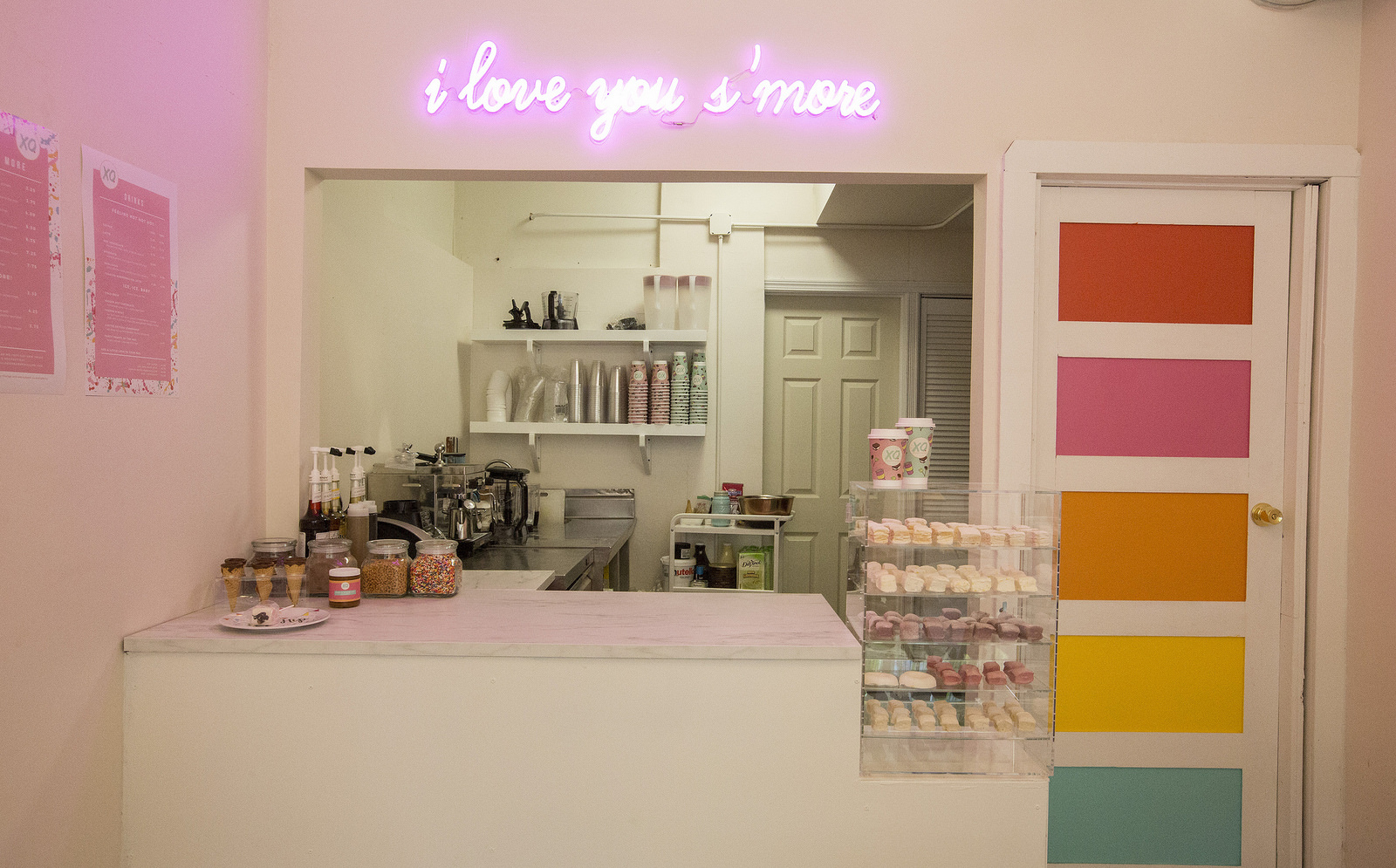 A pink counter with displays of marshmallows and disposable cups.