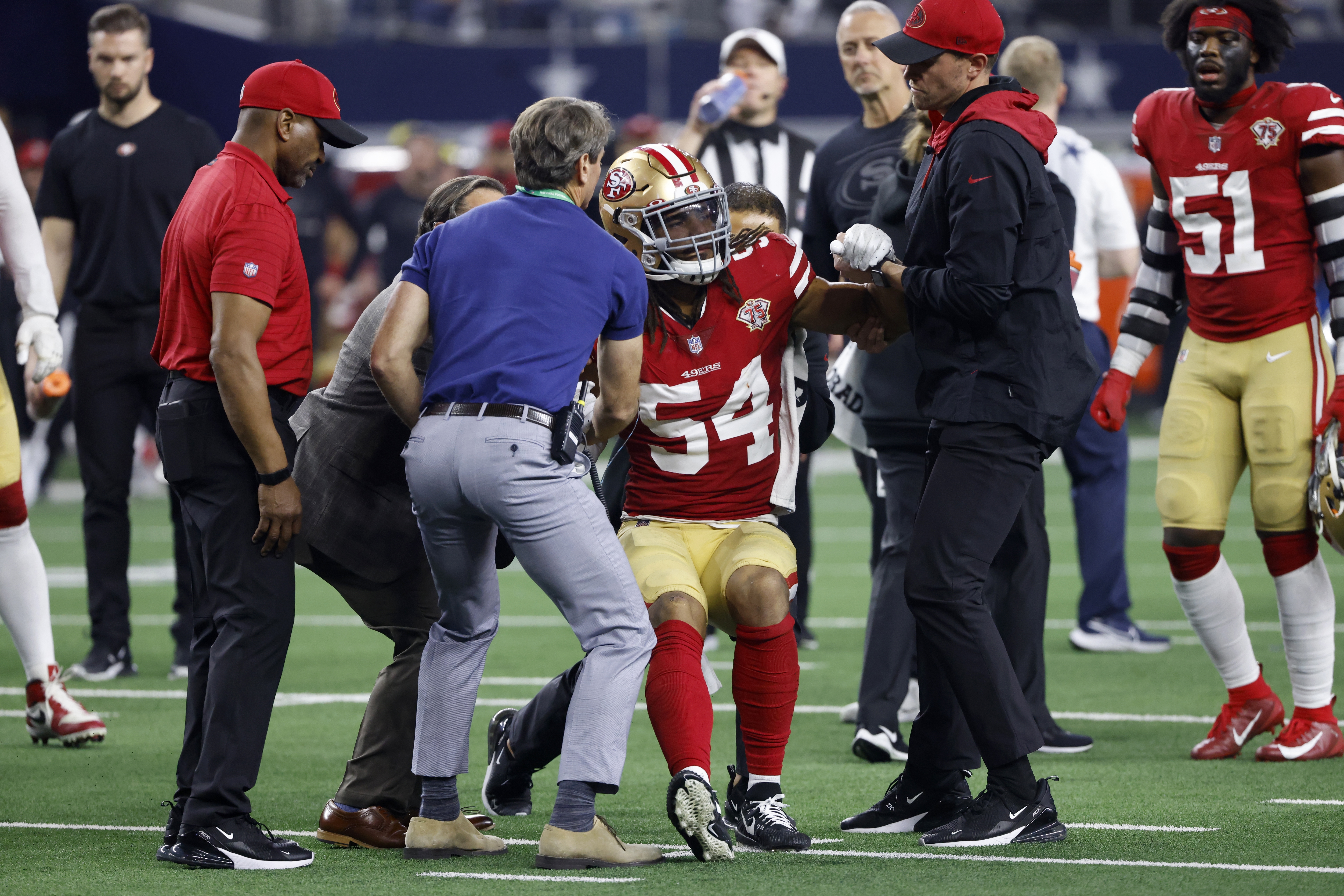 San Francisco 49ers middle linebacker Fred Warner (54) is assisted by team staff after suffering an injury.