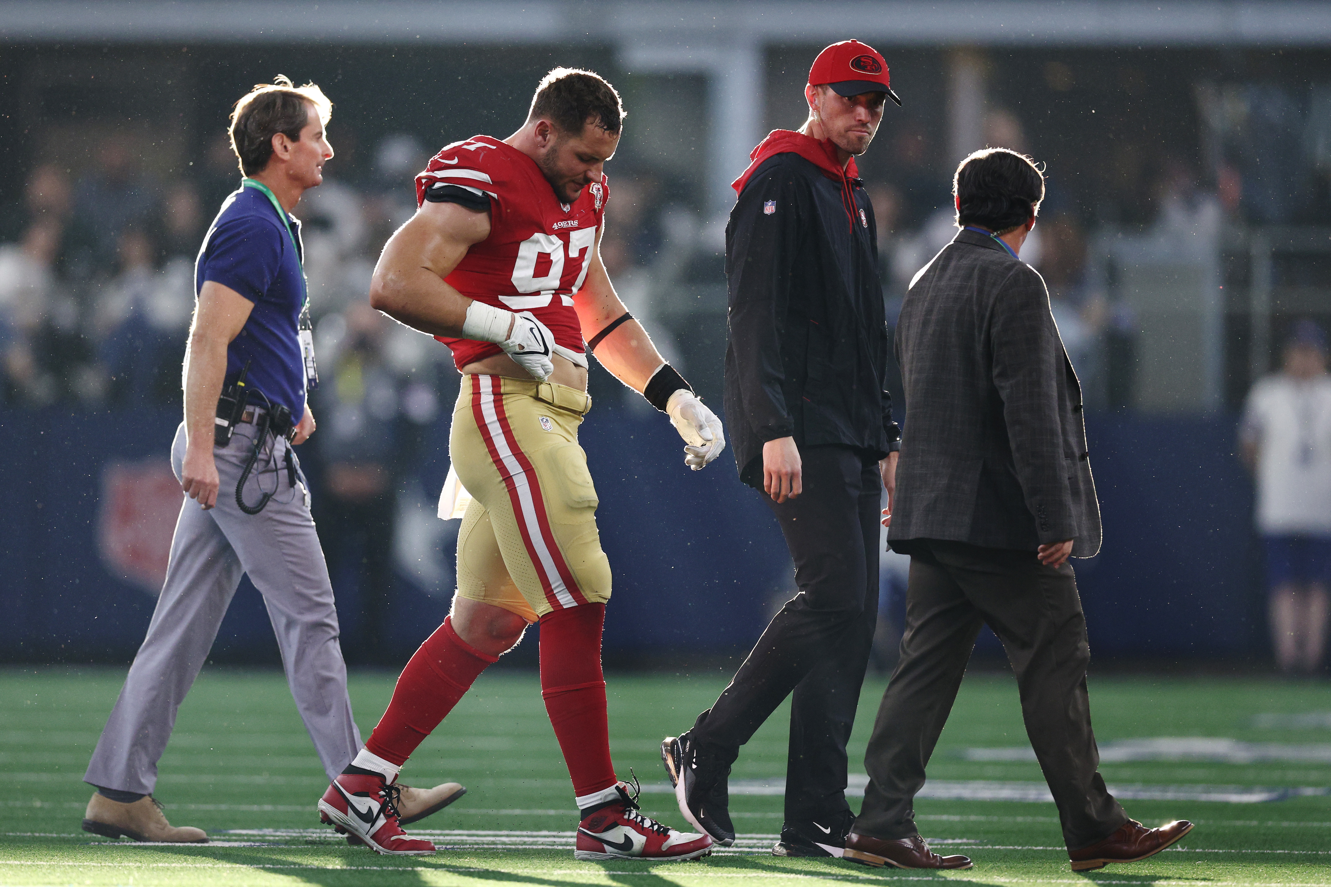 Nick Bosa #97 of the San Francisco 49ers walks off the field after an injury against the Dallas Cowboys during the second quarter in the NFC Wild Card Playoff game at AT&amp;T Stadium on January 16, 2022 in Arlington, Texas.