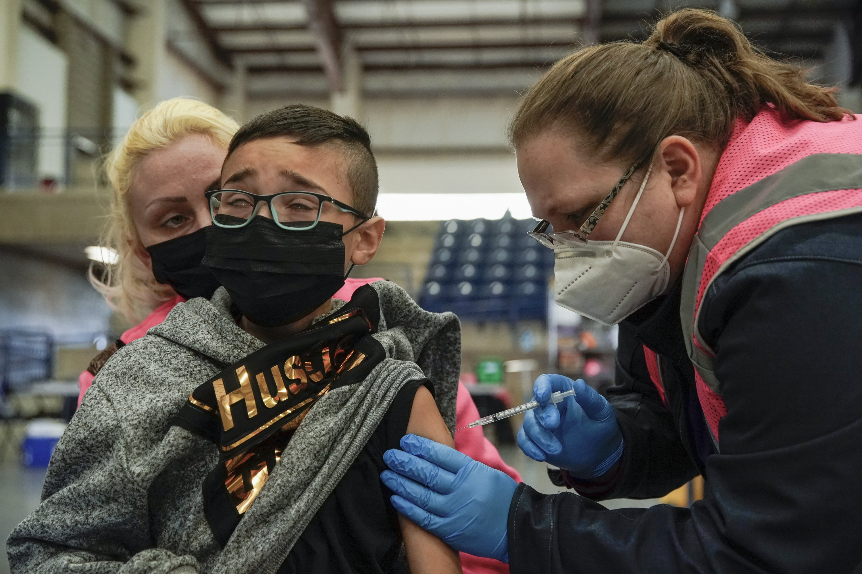 Registered nurse Clarece Glanville gives Daymien Dennis-Garcia, 9, his first dose of COVID-19 vaccine as his sister, Kalizsa, holds him at the Legacy Events Center in Farmington on Monday, Jan. 24, 2022.