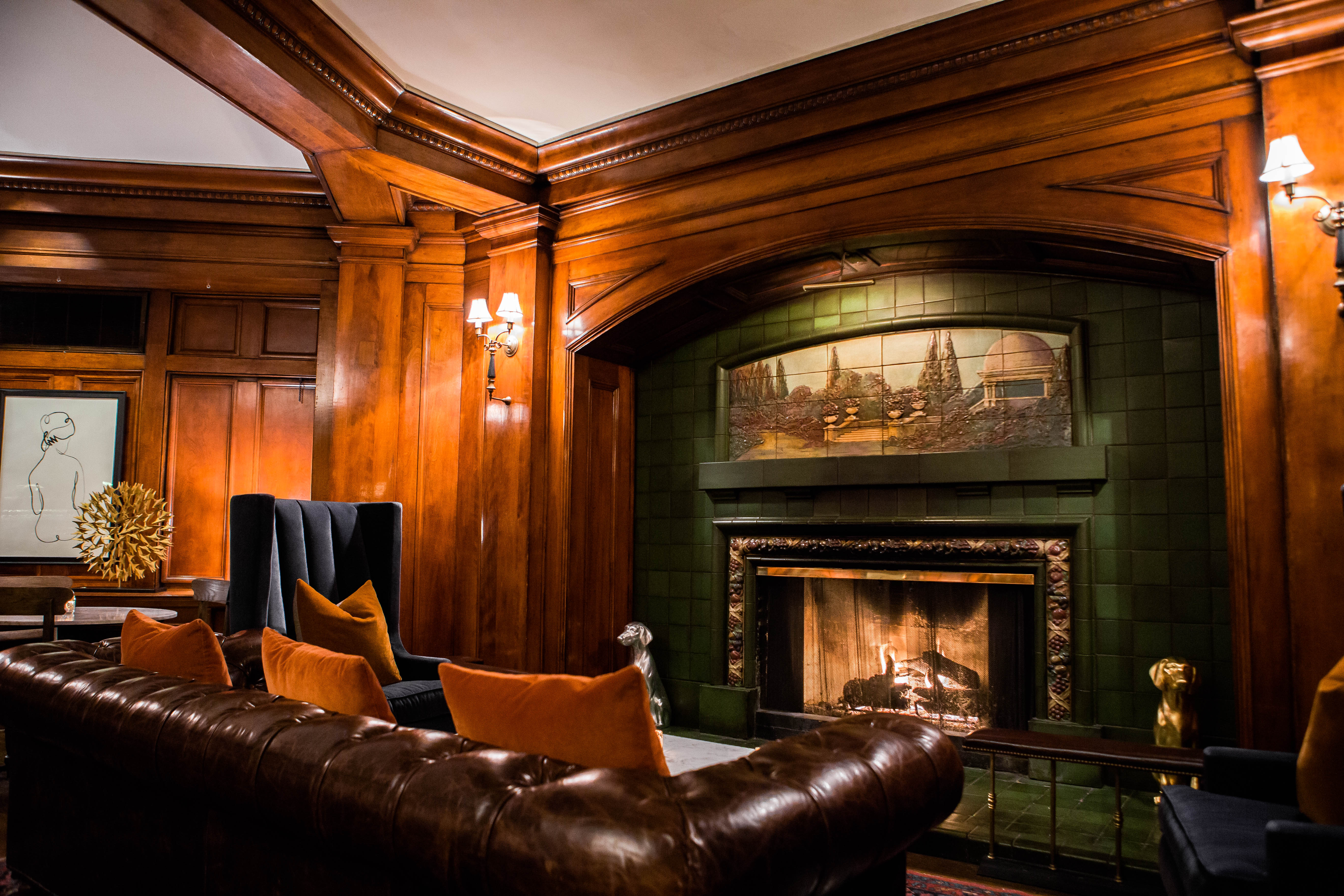 A brown leather couch next to a fireplace