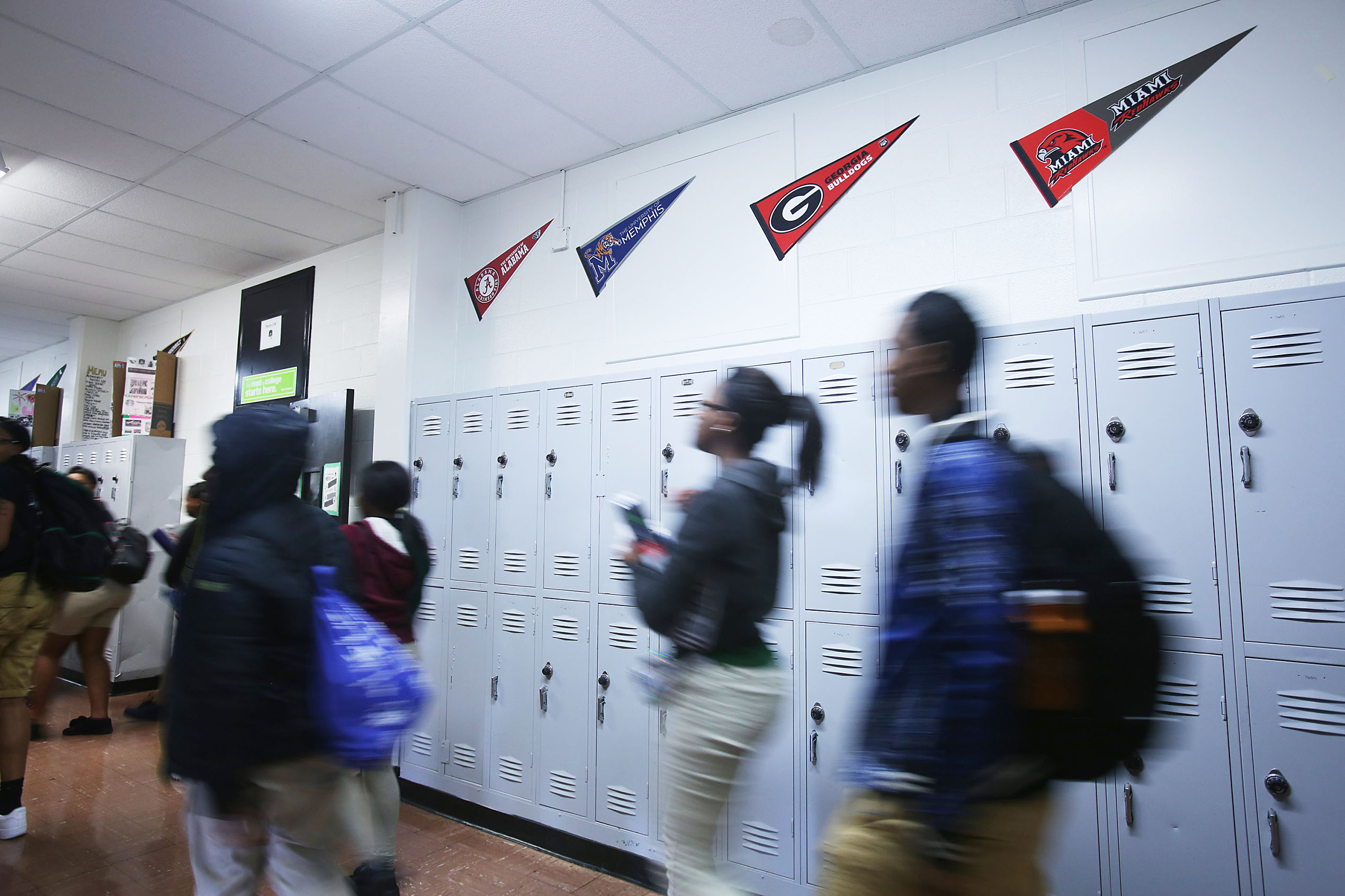 Students walk in a hallway past lockers at a high school in the Achievement School District.
