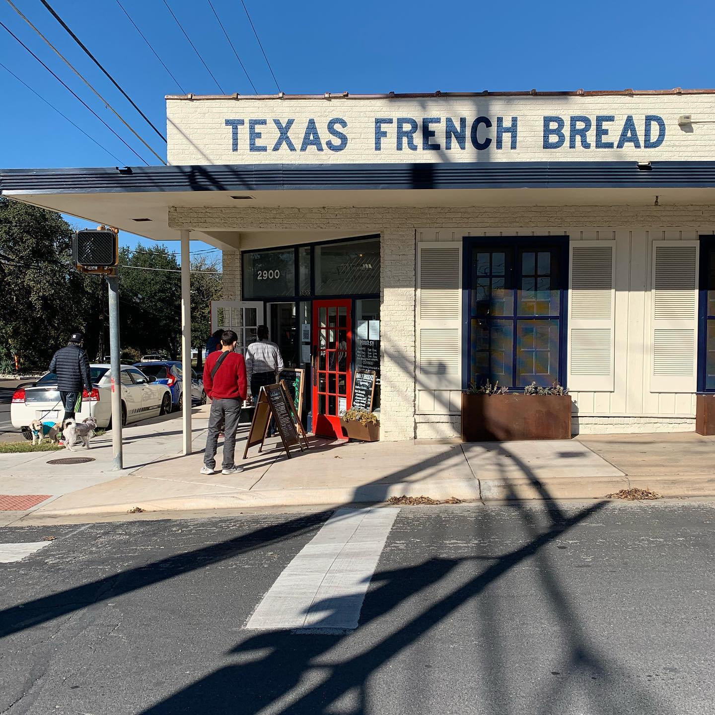 A restaurant building with the name “Texas French Bread” on top, and people are  waiting to enter.