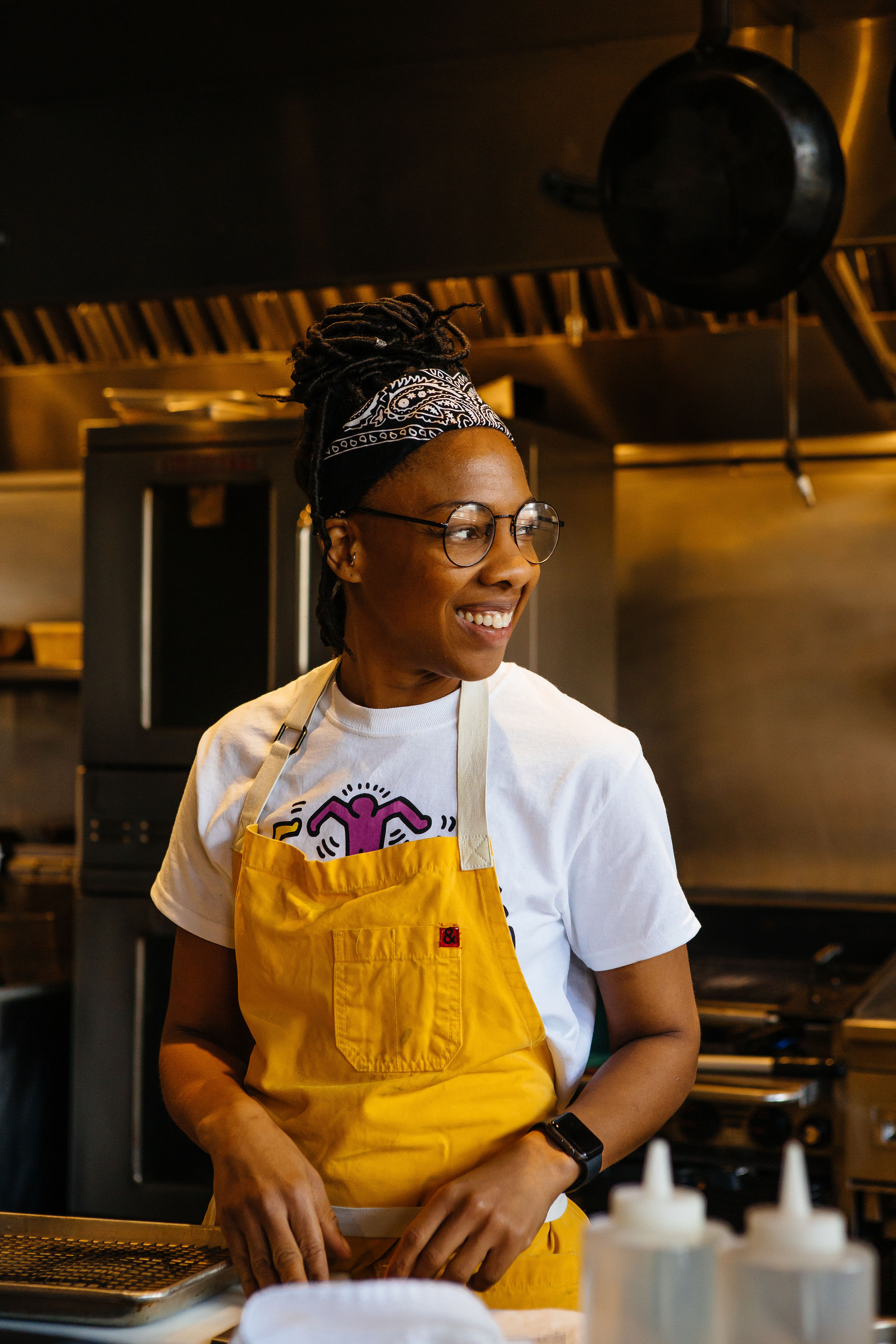 Young Black woman in an apron, smiling. 