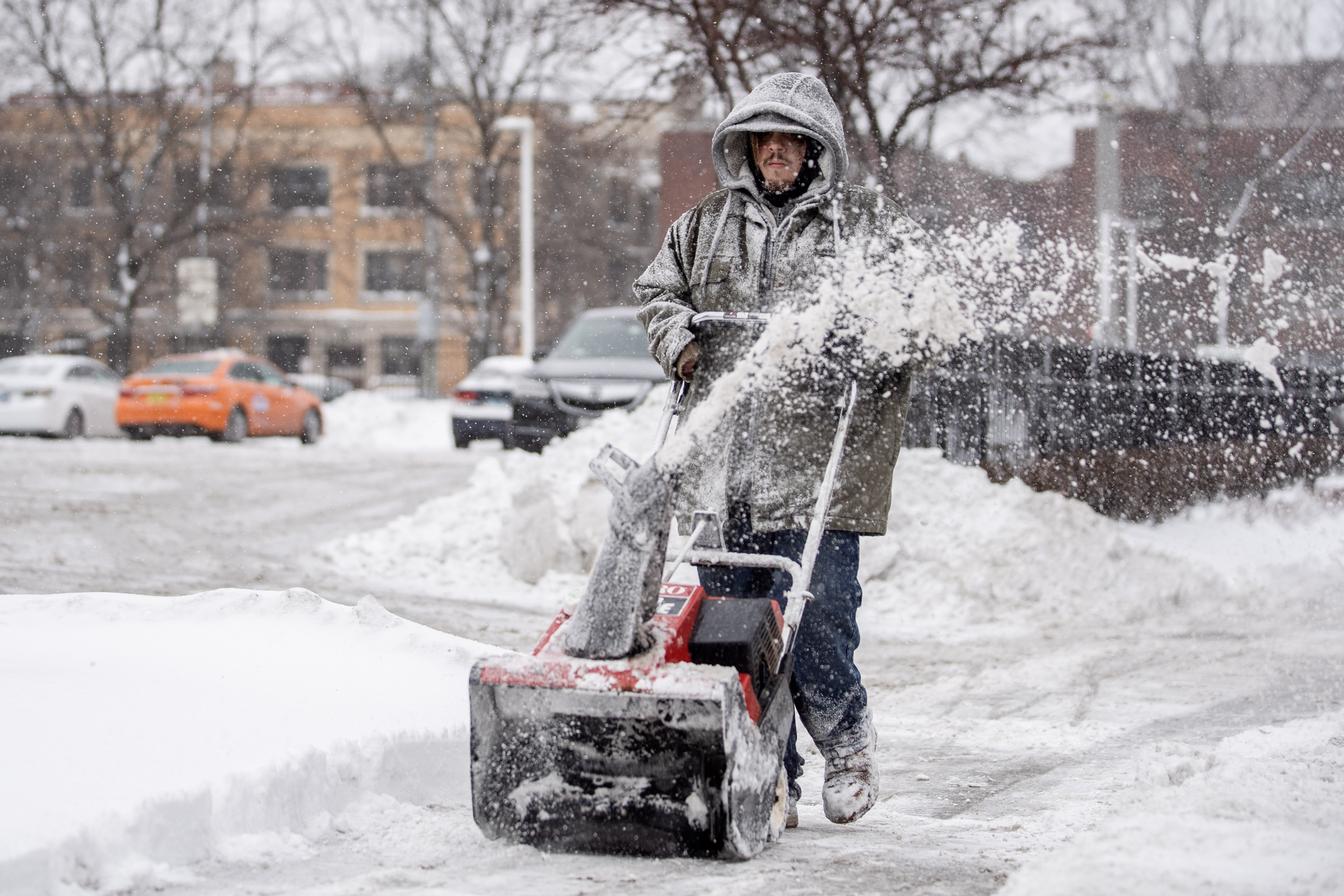 A worker clears snow on the sidewalk of North Sheridan Road in the Lake View neighborhood, Friday morning, Jan. 28, 2022, as lake effect snow enveloped Chicago.
