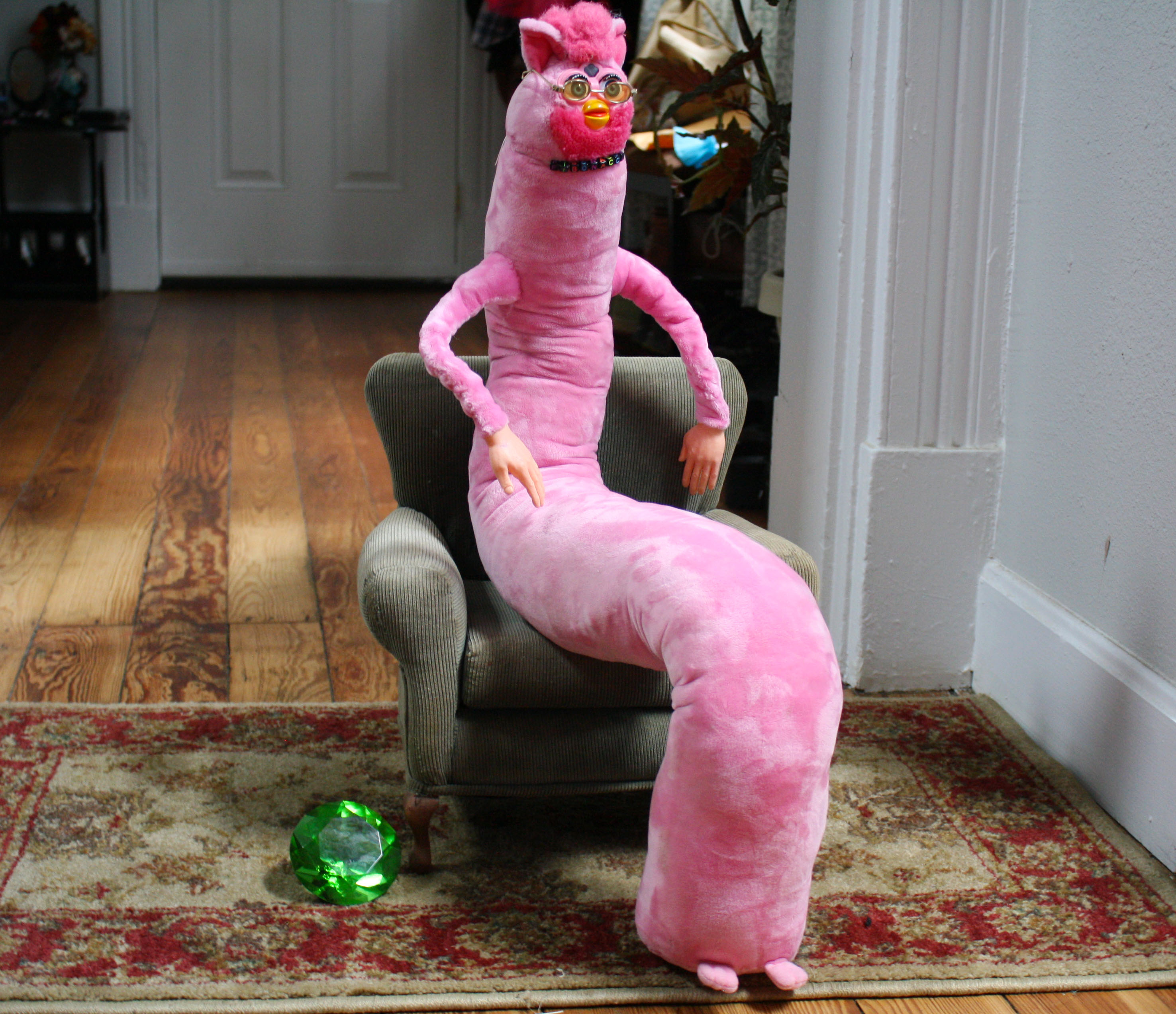 A pink LongFurby sitting in an armchair