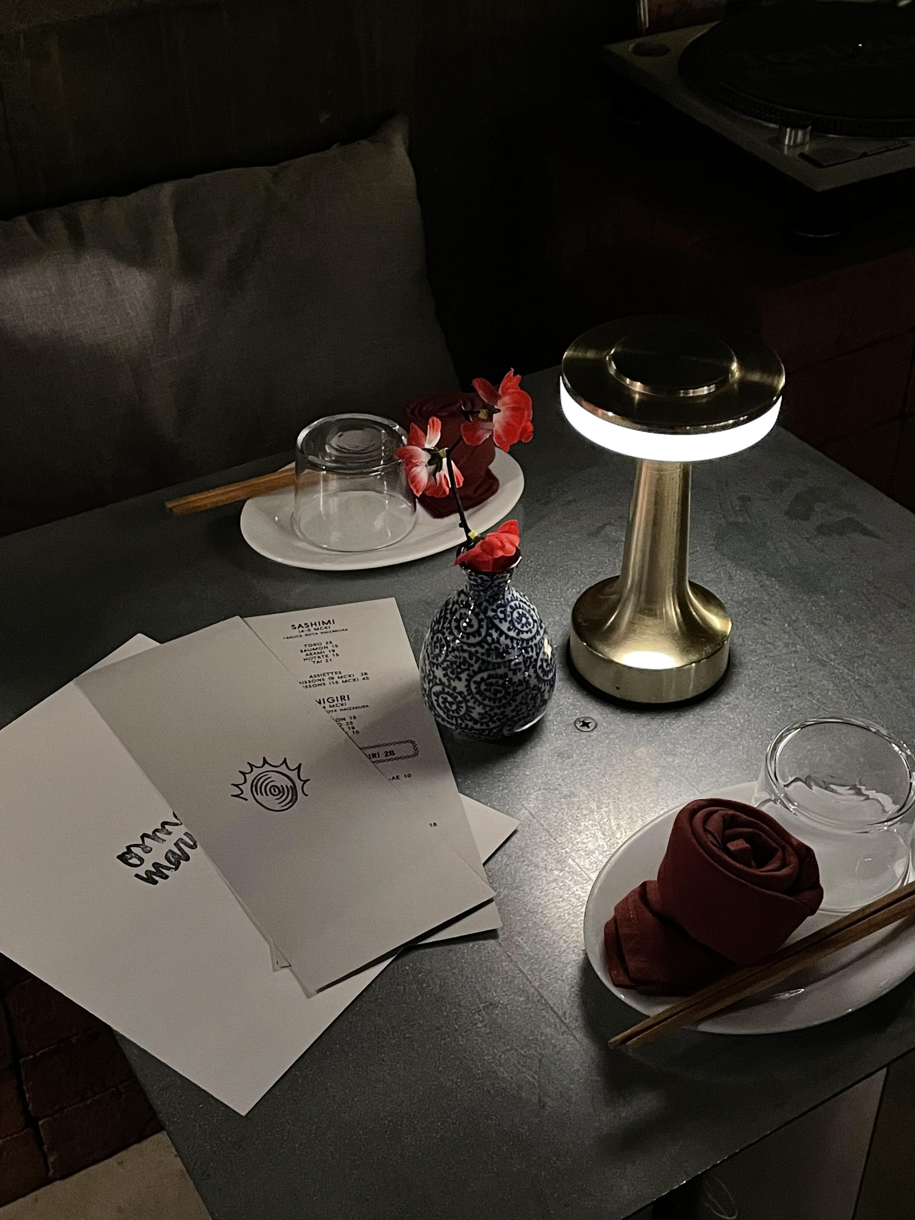 灯光昏暗的桌子，花瓶里的红花