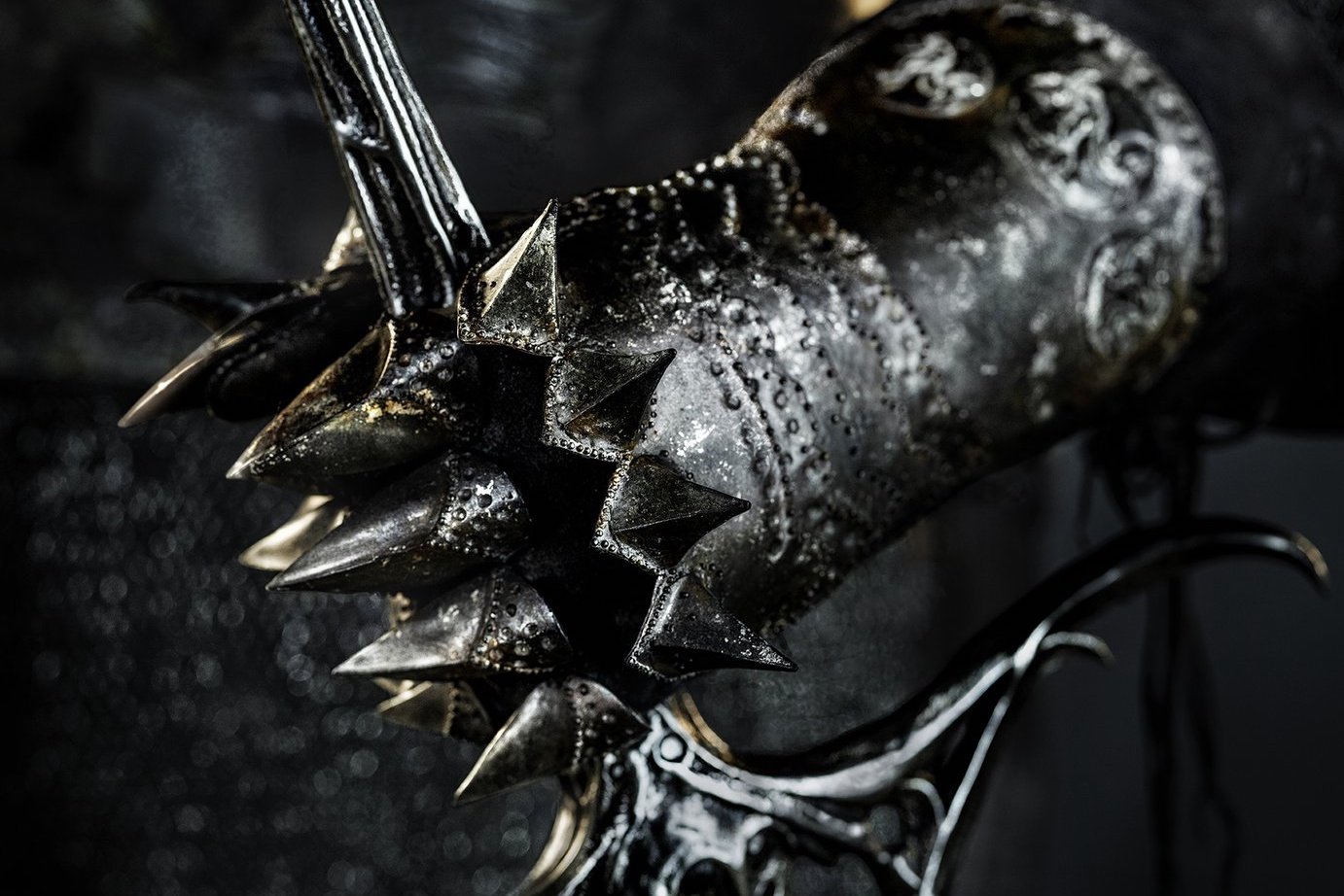 A very Sauron-like gauntlet grips the hilt of a weapon in a character poster for The Lord of the Rings: The Rings of Power.