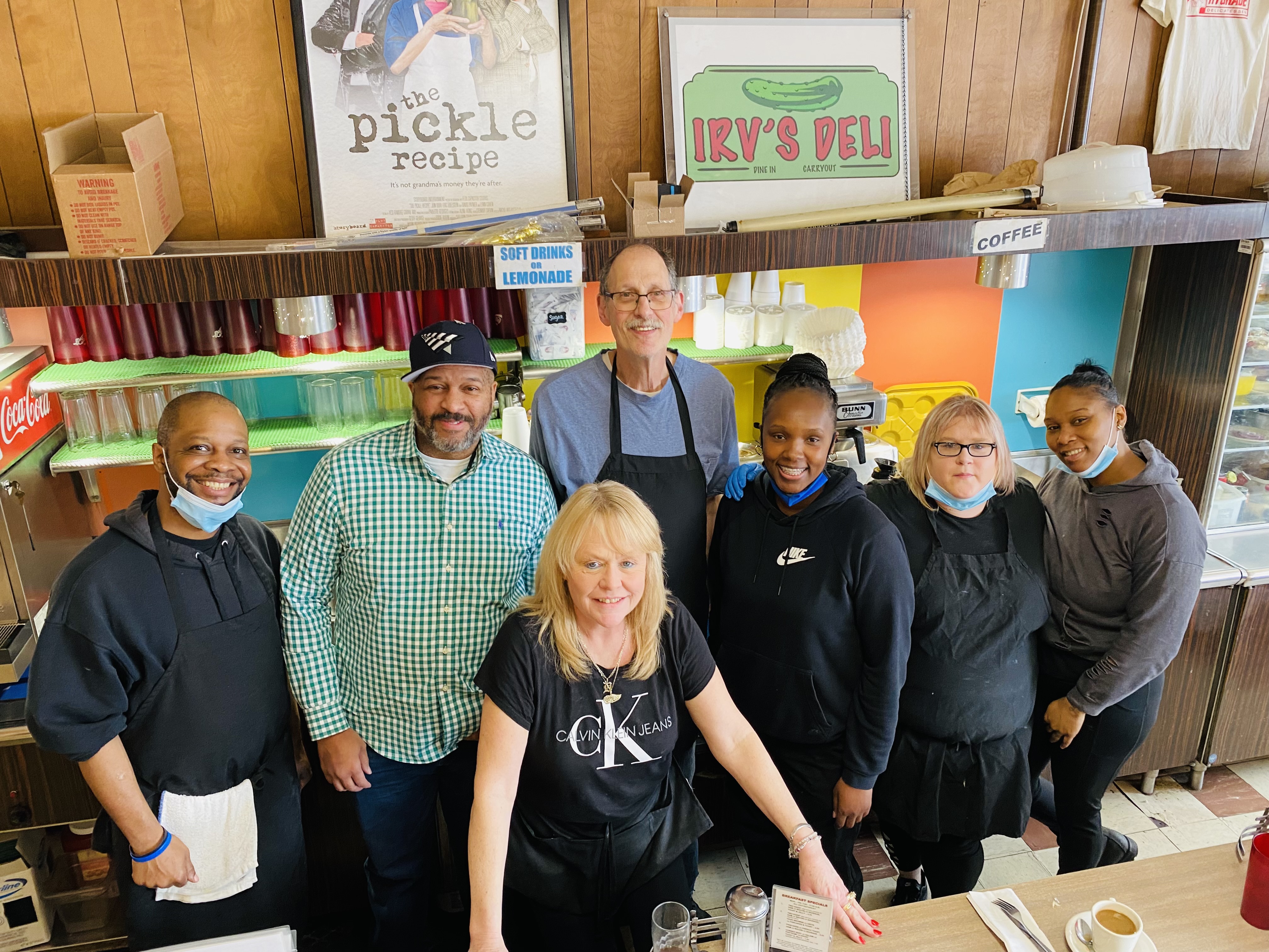 在密歇根州底特律市的Hygrade熟食店，七个微笑的人站在午餐柜台后面。