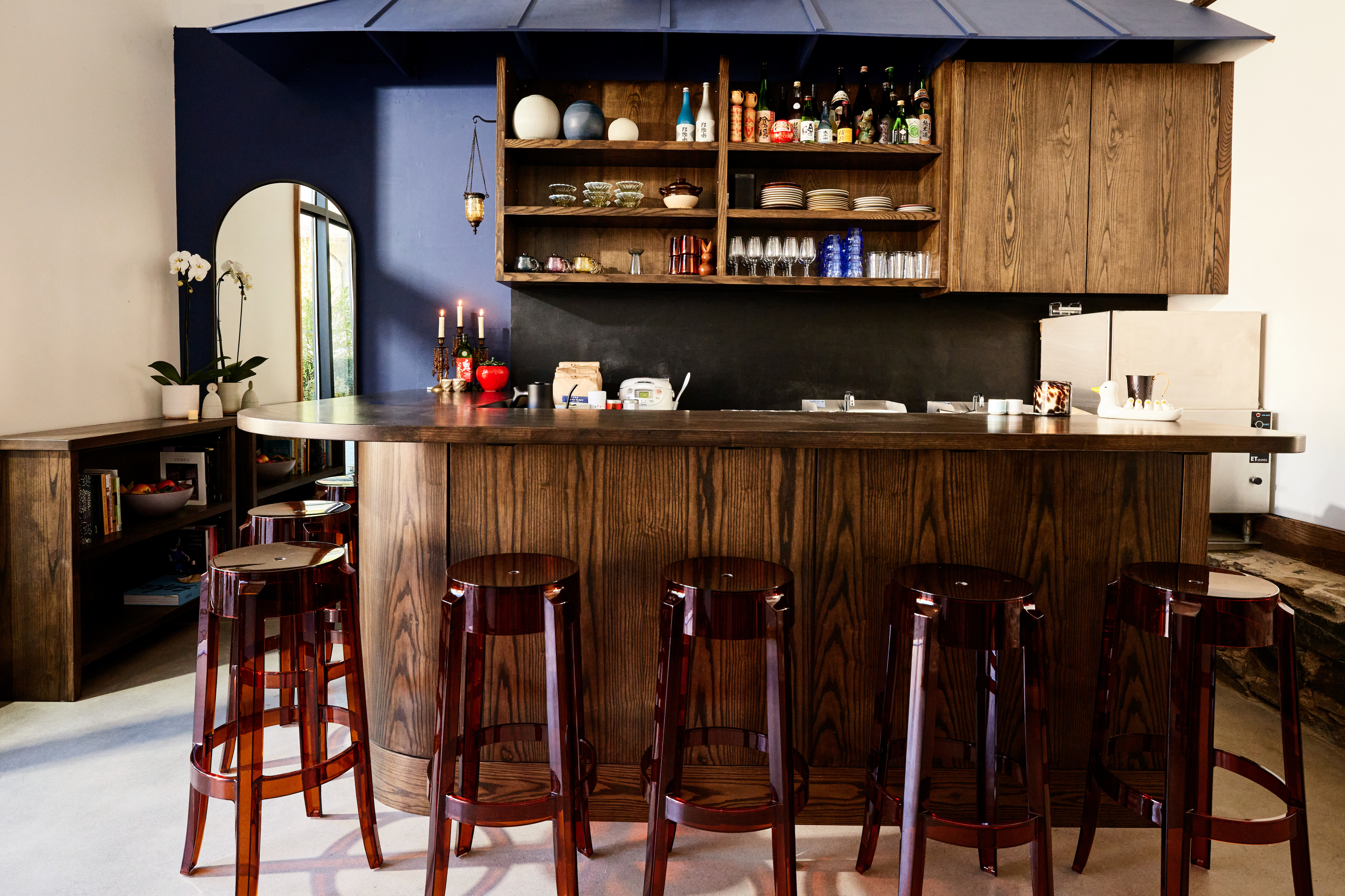 一个小缘住的酒吧的内部与半透明的红色酒吧凳子和一个弯曲的木酒吧。