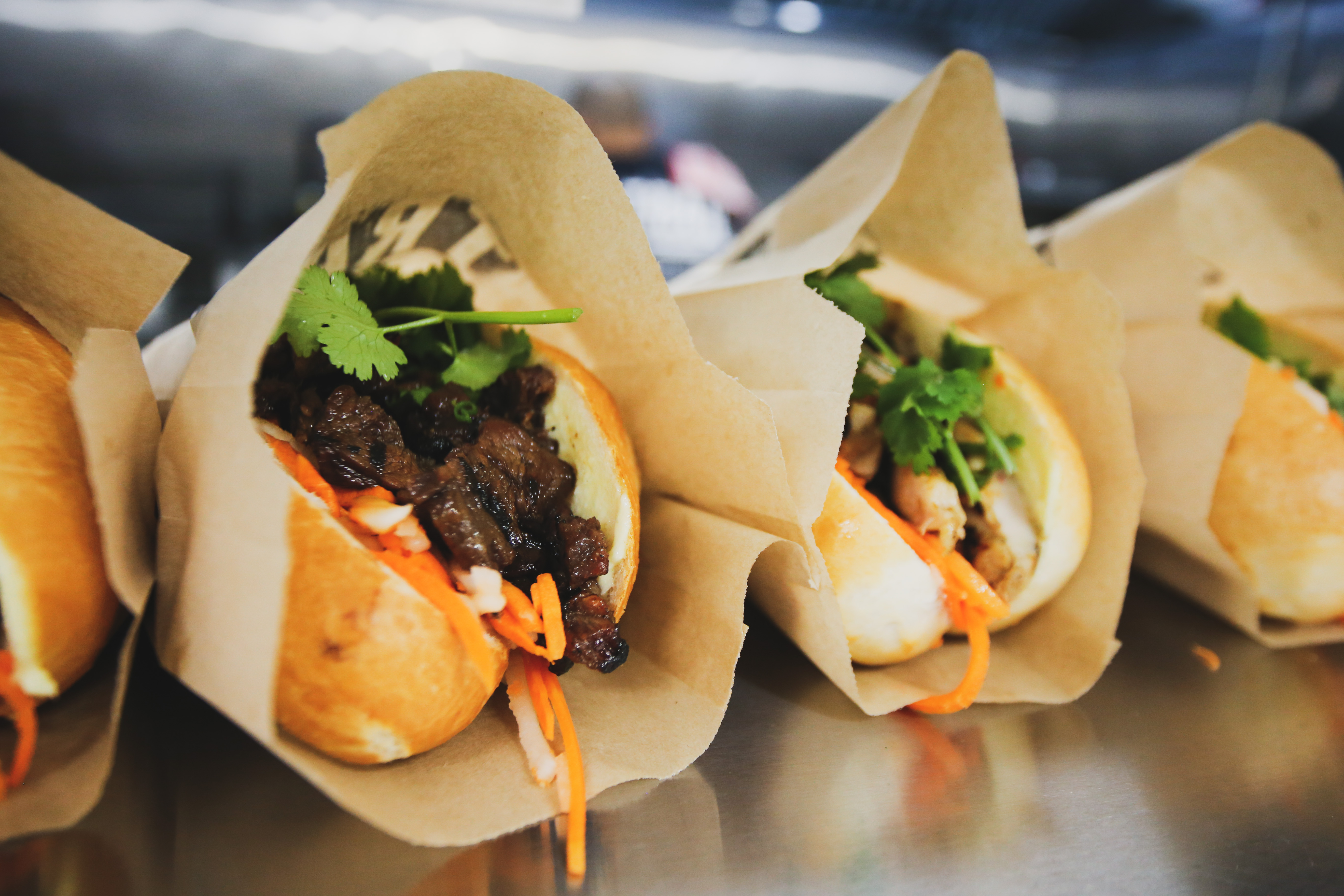 four banh mi in paper bags