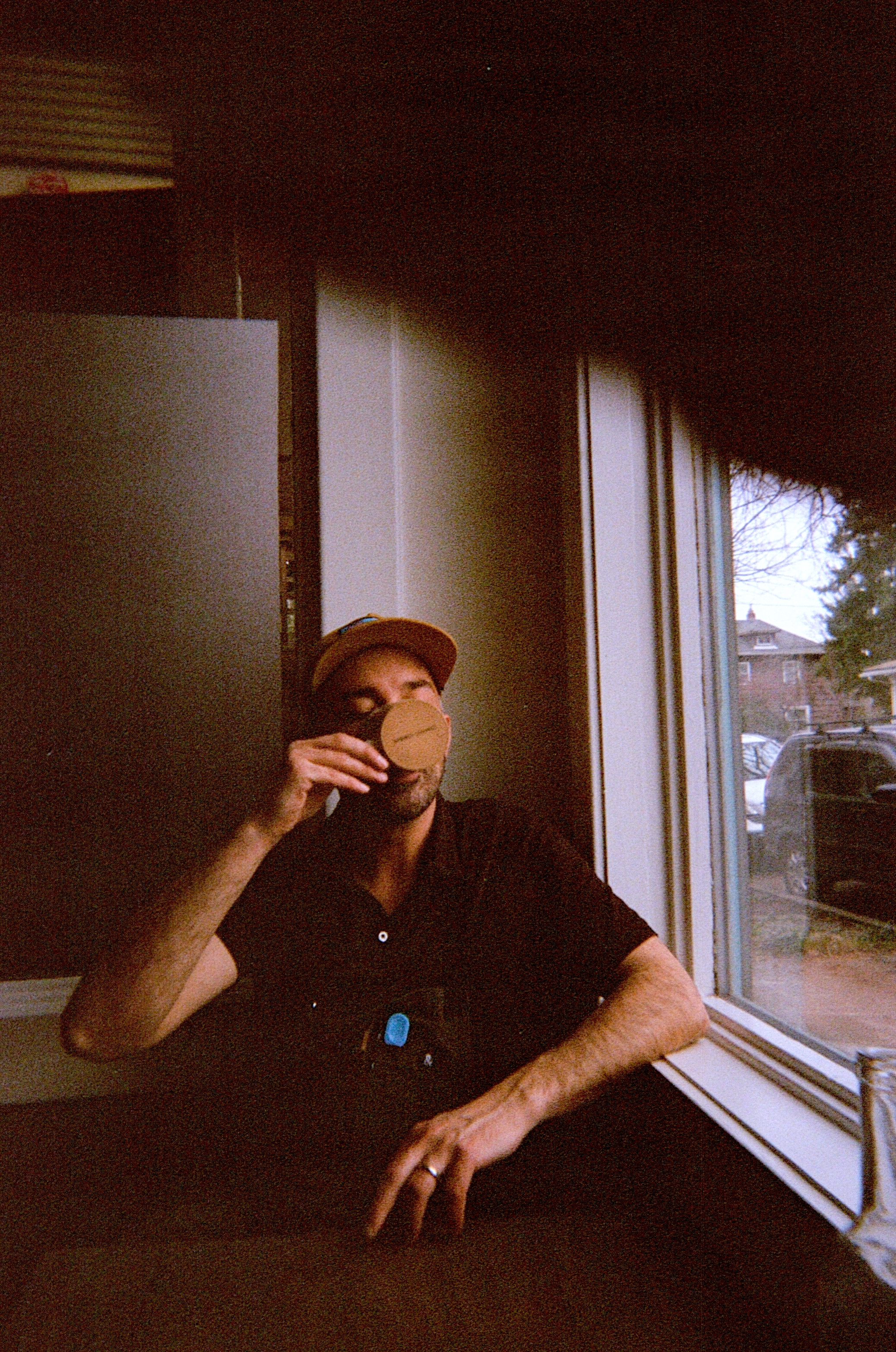 A man sits in the window of Jacqueline drinking a cup of coffee.