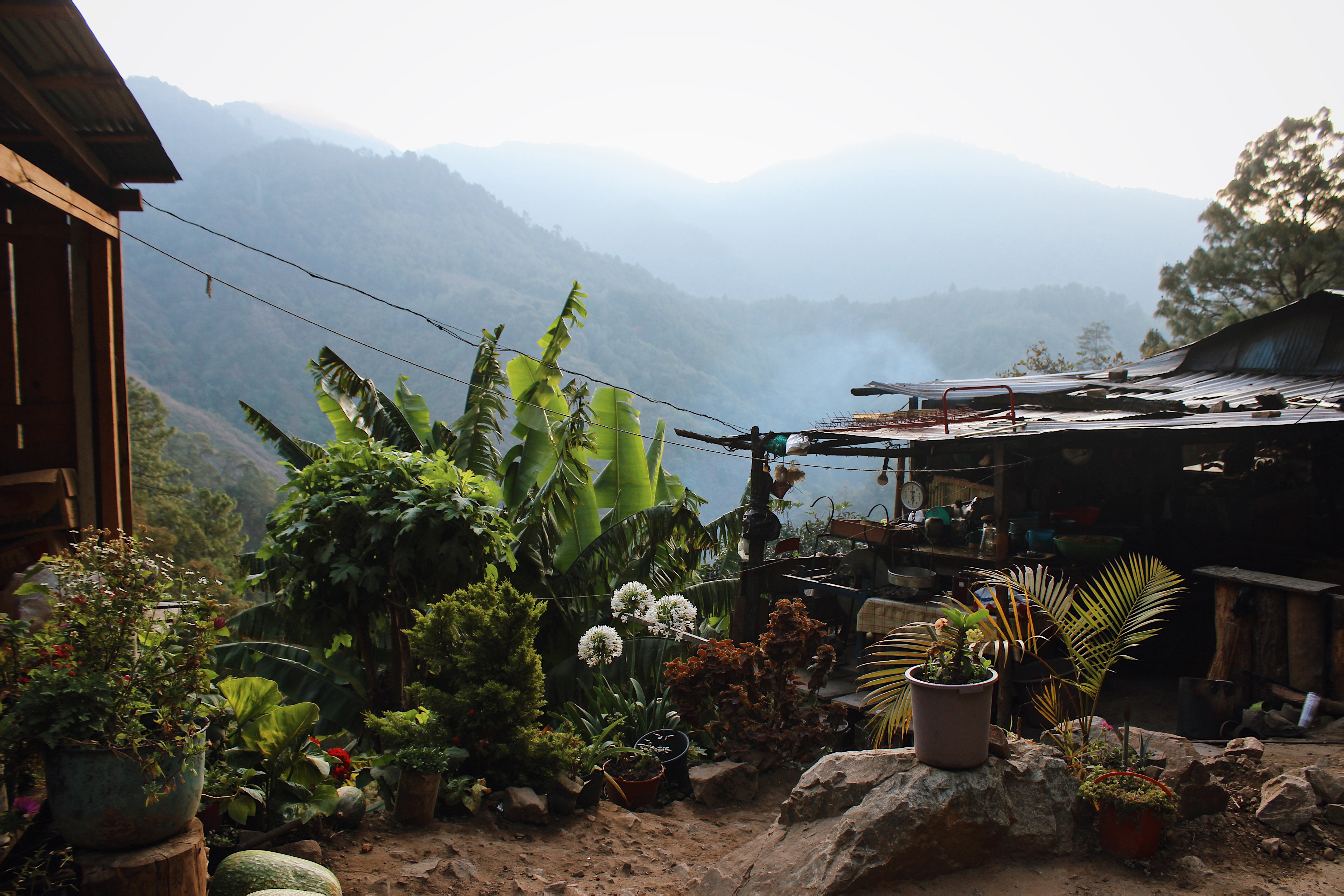A tin roof structure sits on the side of a road with misty mountains in the background. 