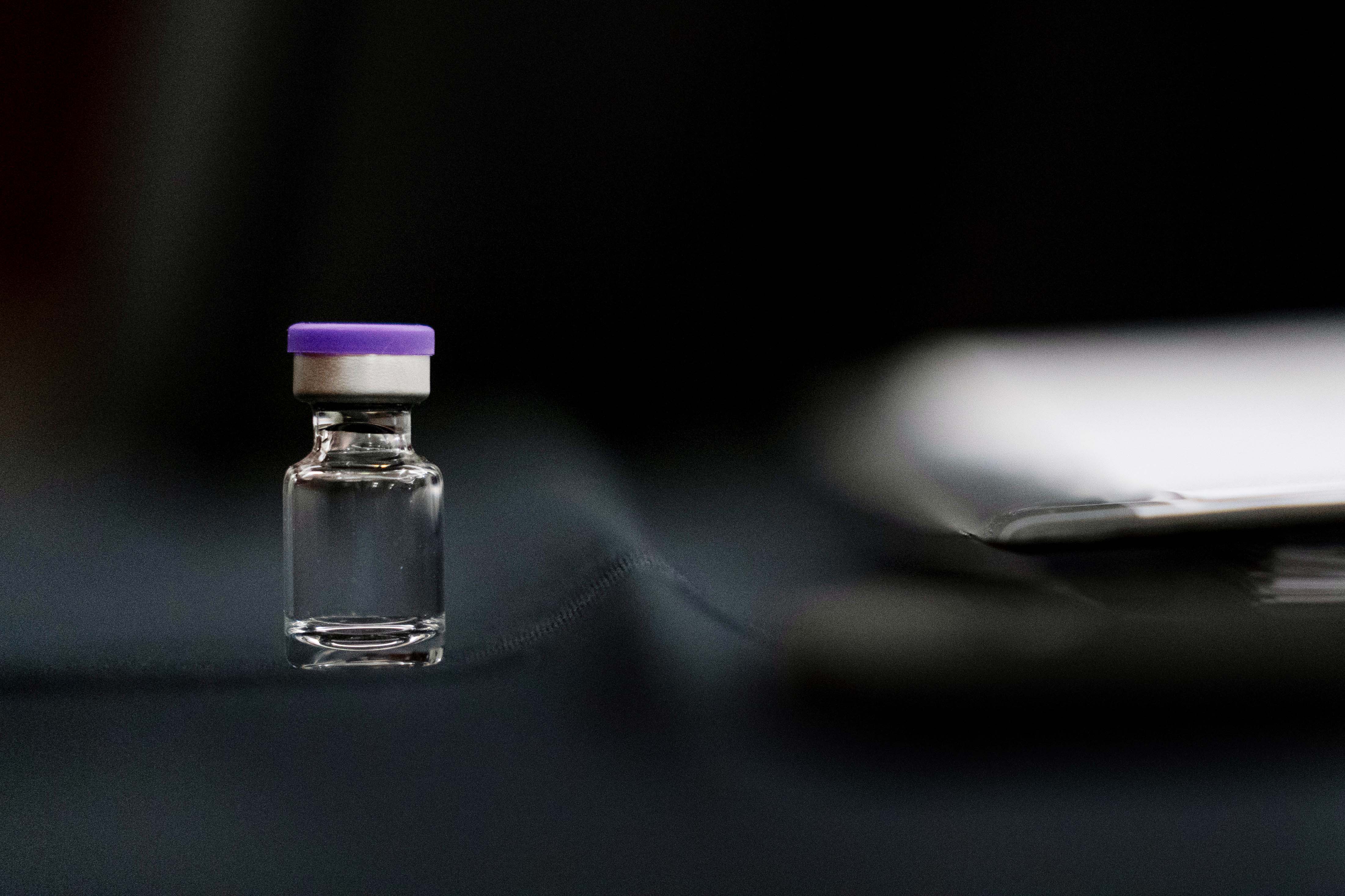 A vial of vaccine on a desk.