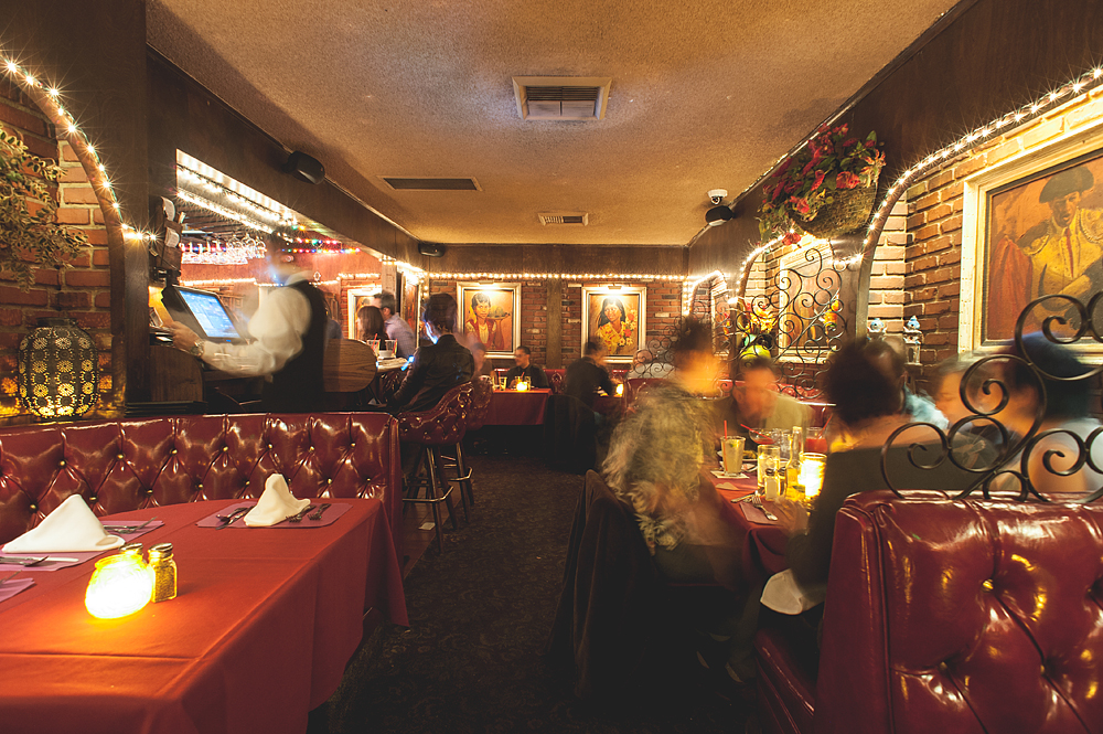 Inside the historic, dimly lit dining room of Casa Vega with diners tucked into red booths.