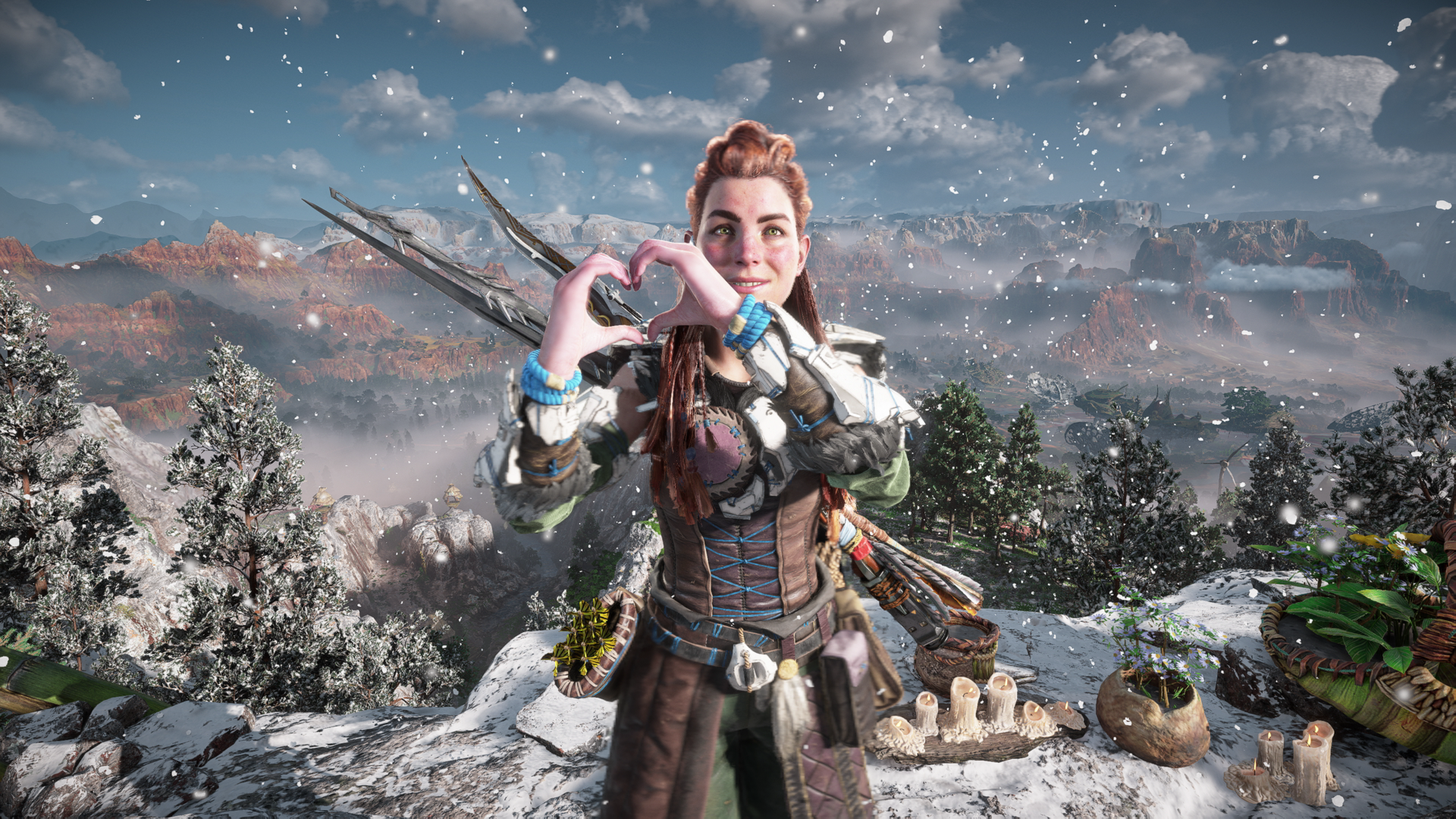 Aloy smiles at the camera, making a heart shape with her hands, in a snowy landscape in Horizon Forbidden West
