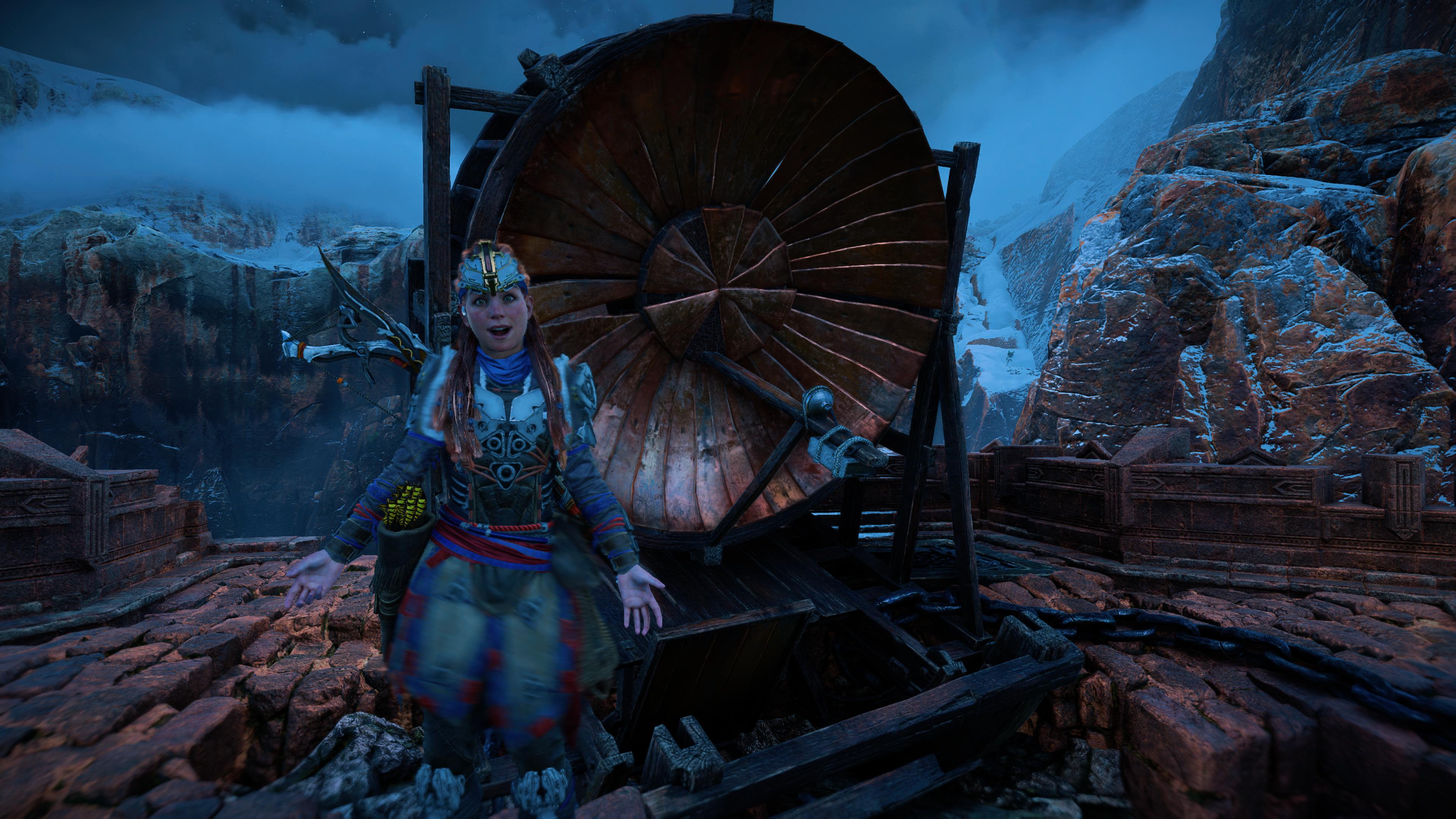 Aloy smiling in Horizon Forbidden West as she stands atop a Carja signal tower, in front of a signal device, which holds the lens of dawn signal lens. 