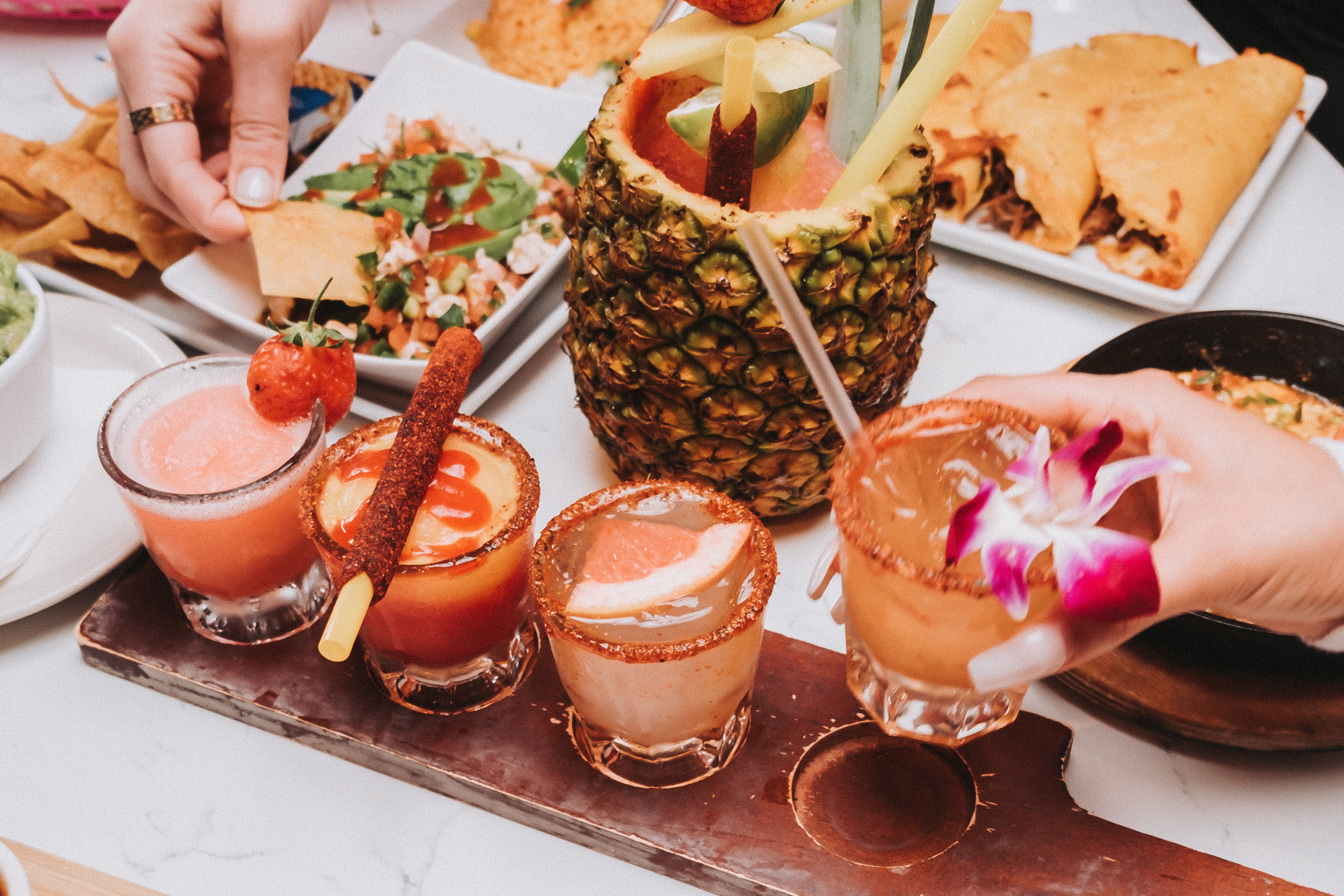 Mexican martinis, margaritas, choriqueso, and birria tacos cover a table.