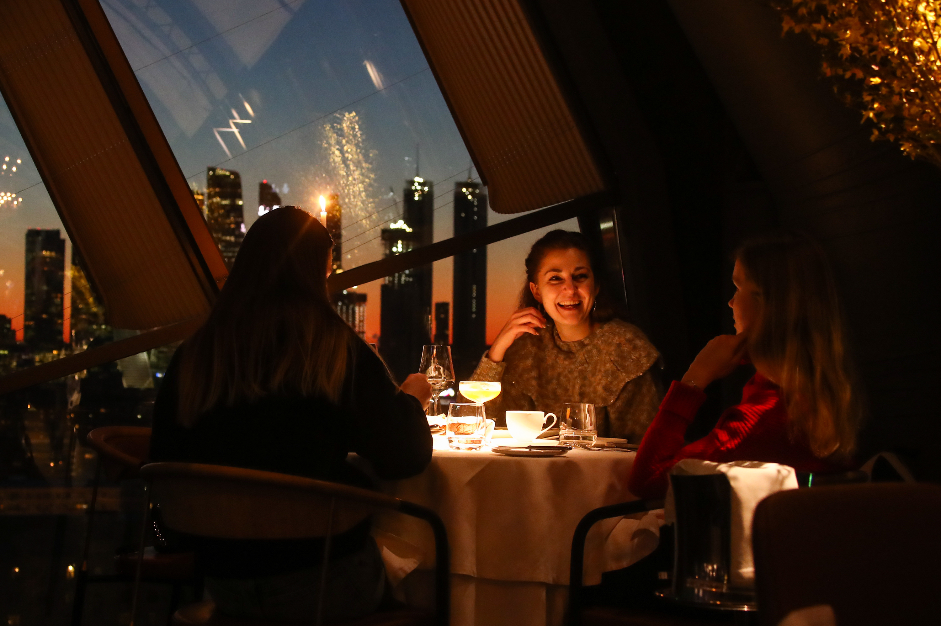 Three women sit at a table in a dark restaurant