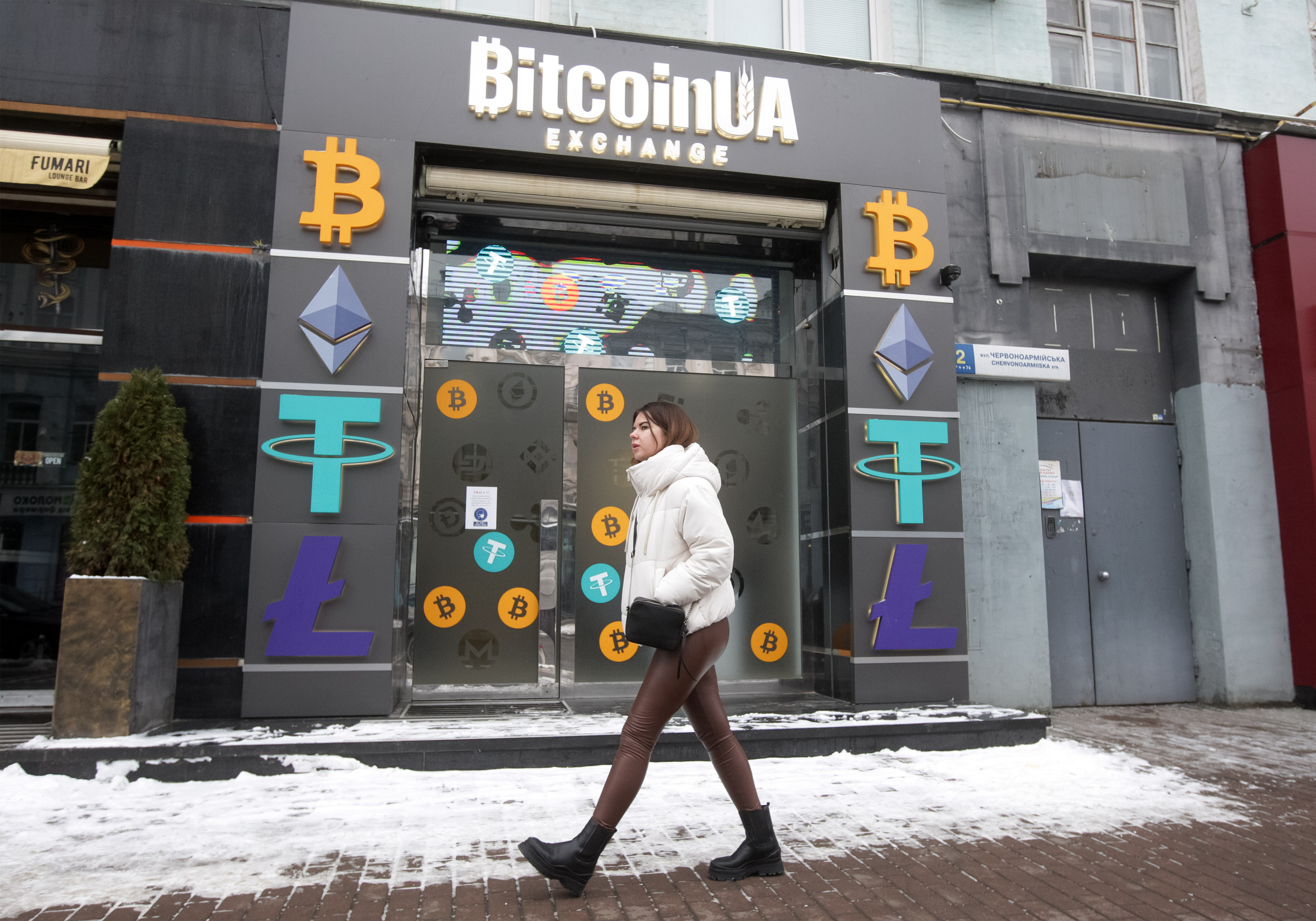 A woman walks past a cryptocurrency exchange point, “BitcoinUA,” in Kyiv, Ukraine.