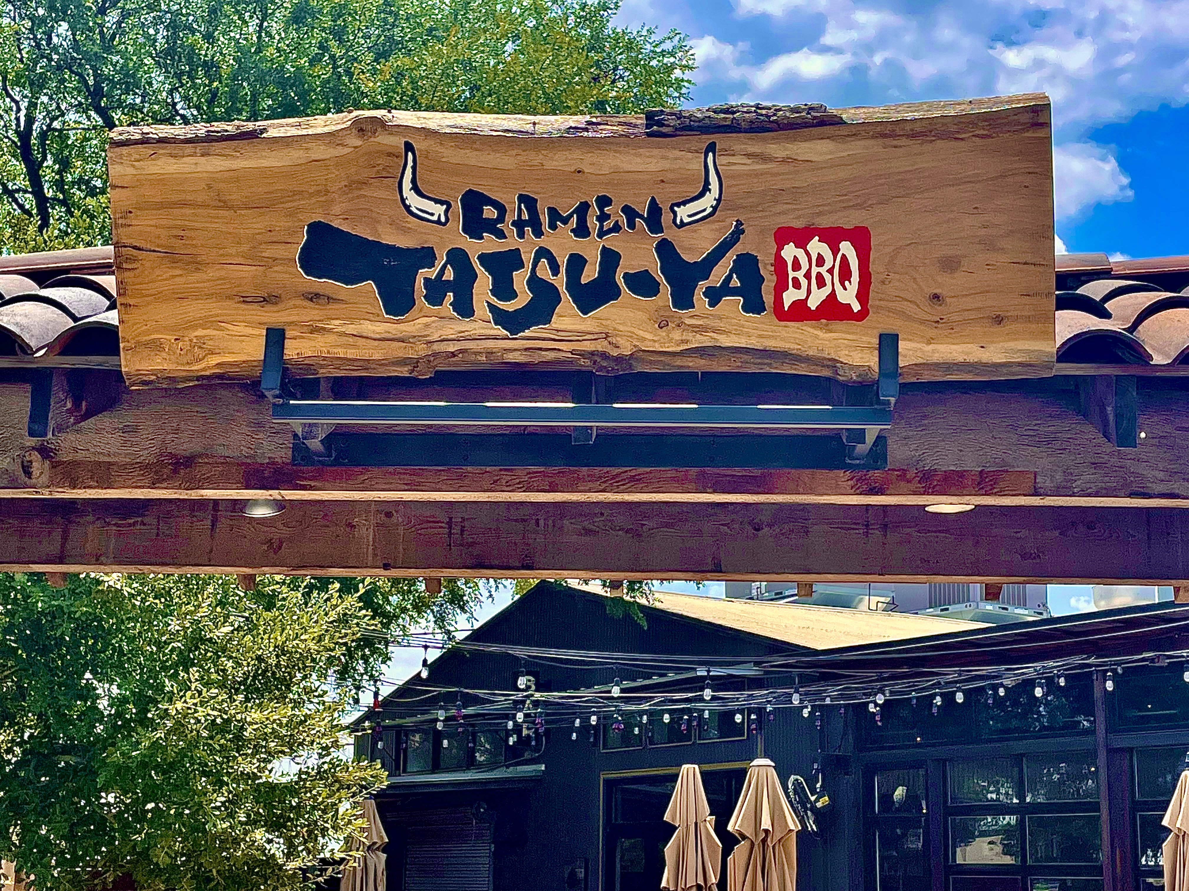 A wooden restaurant sign that reads “Ramen Tatsu-Ya BBQ”