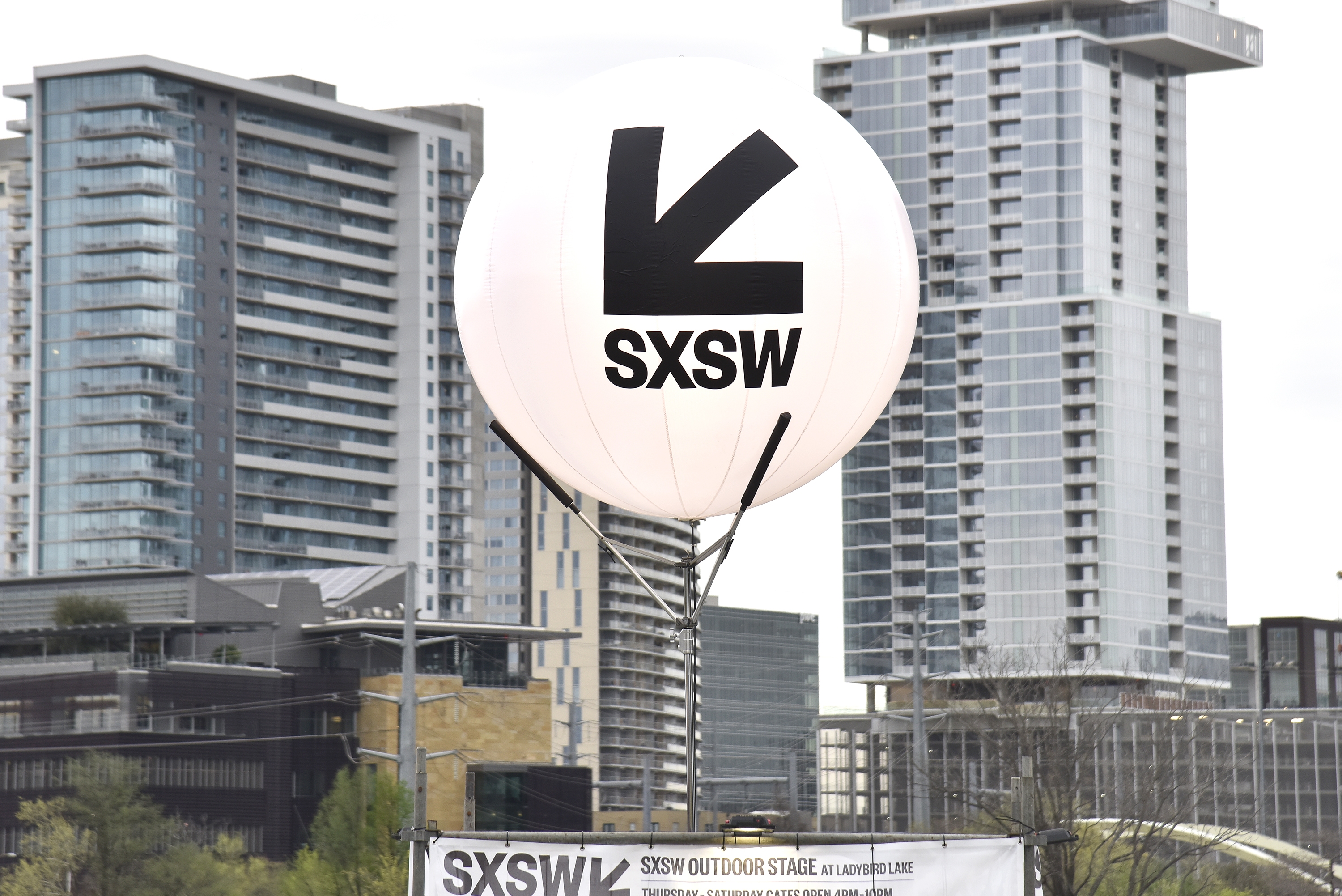 A large white balloon with an arrow pointing to the bottom left and words reading SXSW in front of a city skyline.