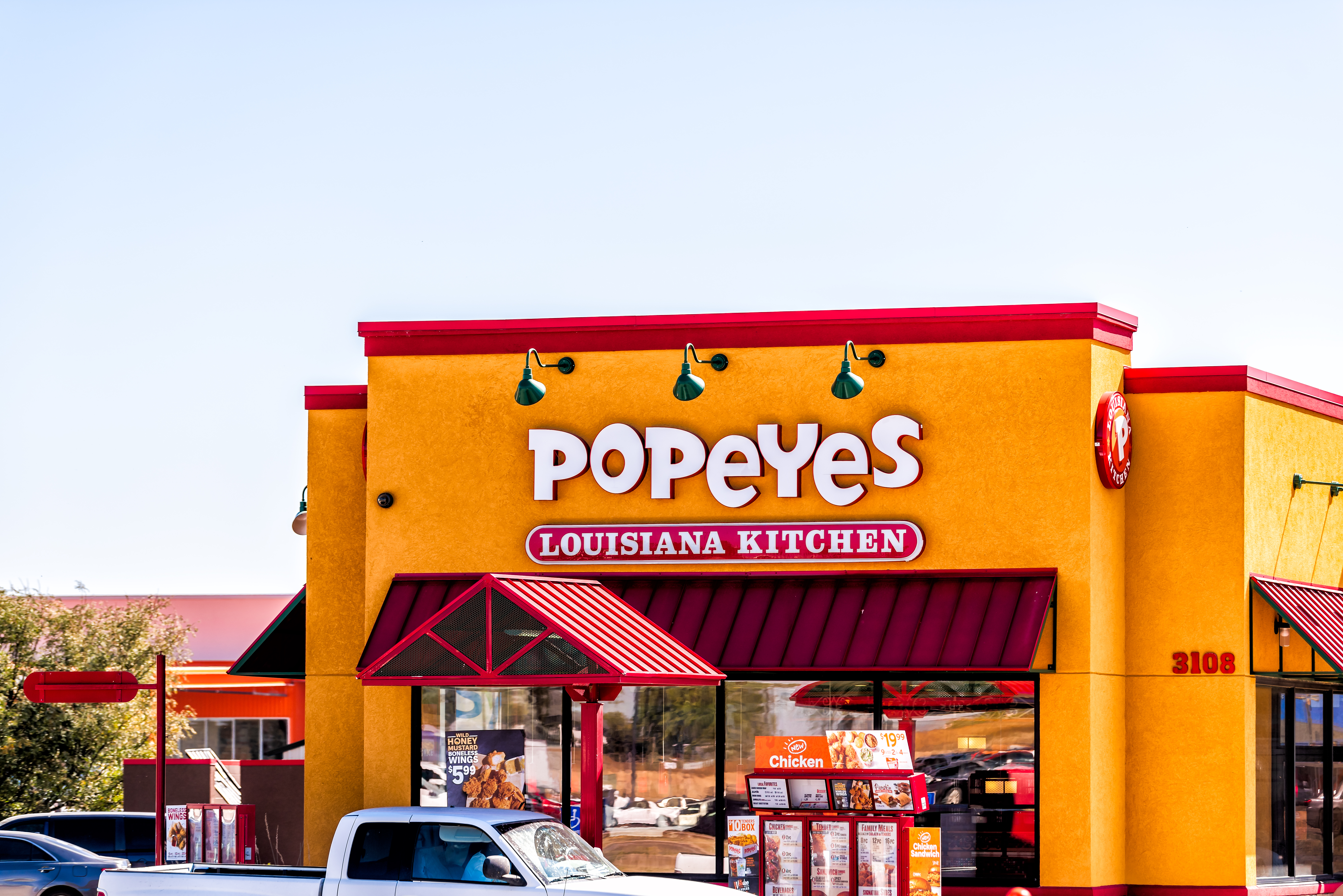 A pickup truck waits at the window of a Popeyes drive-thru.