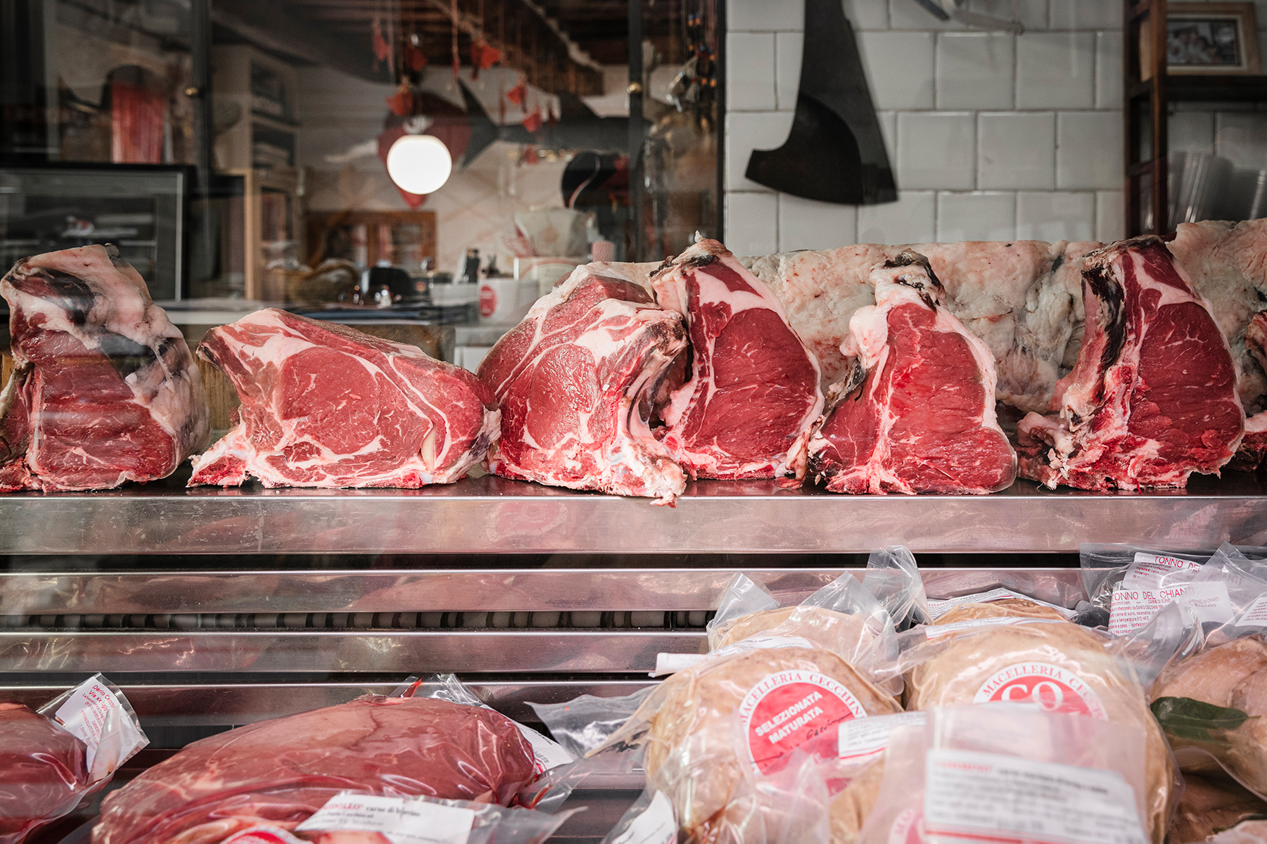 A shelf full of raw meat in a butcher shop.
