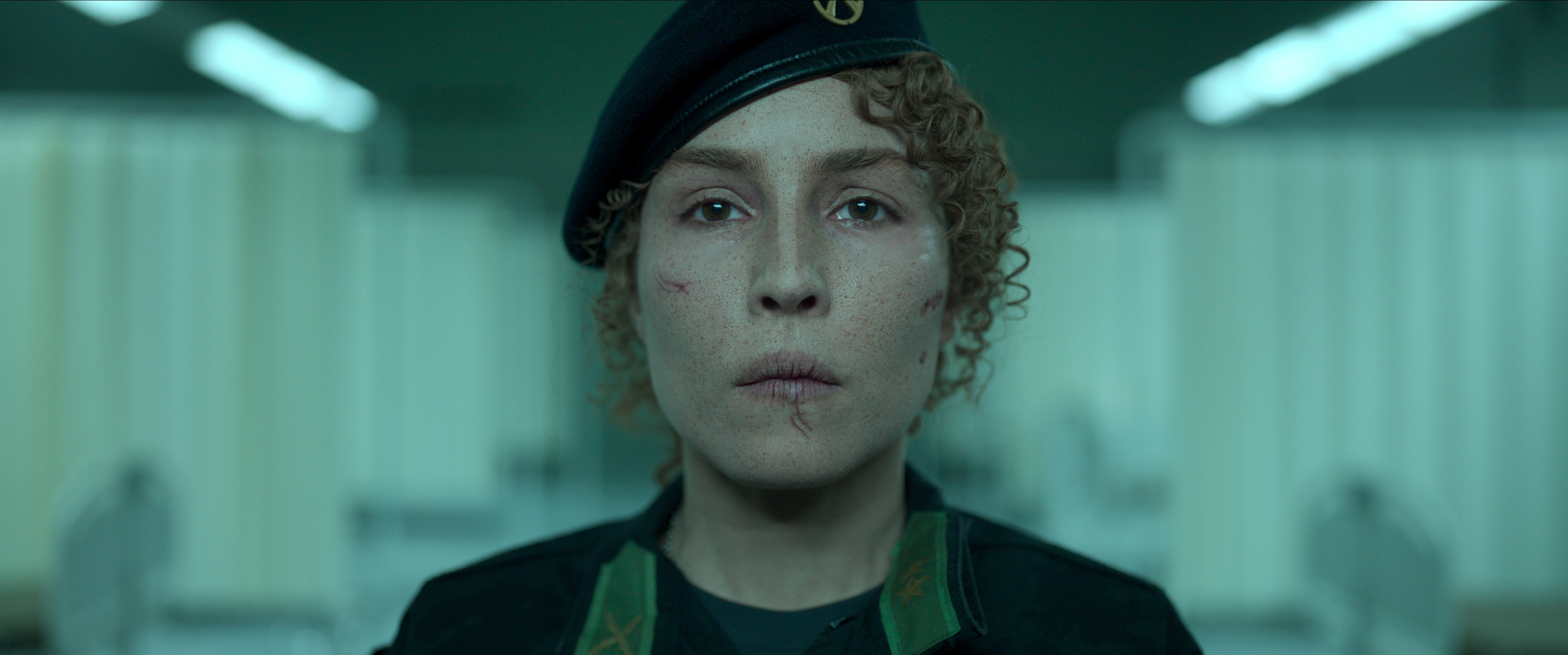 Noomi Rapace stares into the camera wearing military uniform