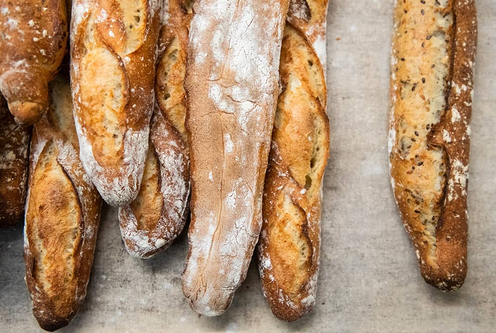 Baguettes made of various flours and toppings, on a neutral background