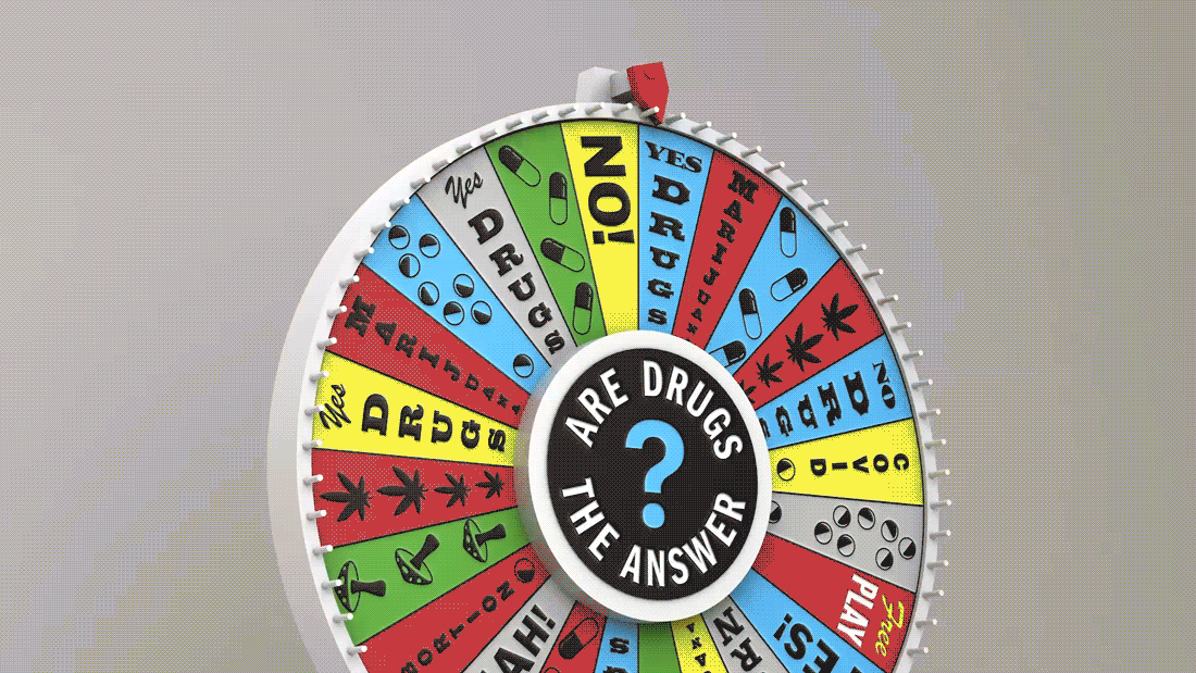 A game wheel spins in front of a muted gray background. Tiles on the wheel say things like “Yes drugs” and “No drugs.”. In the center, the text Are Drugs the Answer forms a circle around a large blue question mark.
